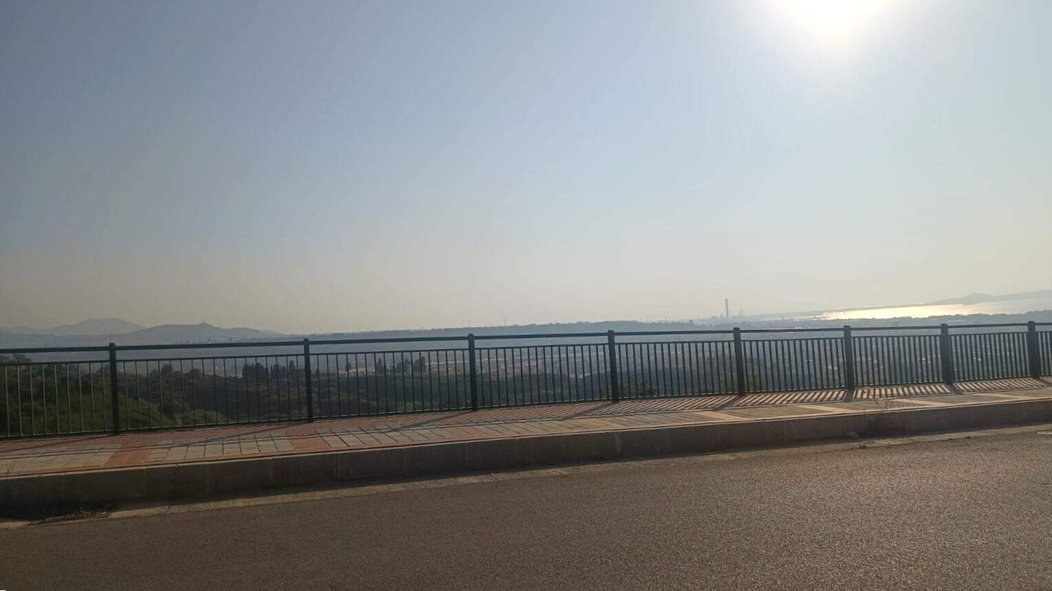 Vismo panoramico sulla città dal terrazzo con ringhiera in metallo, sfondo di colline e cielo sereno, ideale per immagini di immobili e investimenti immobiliari.