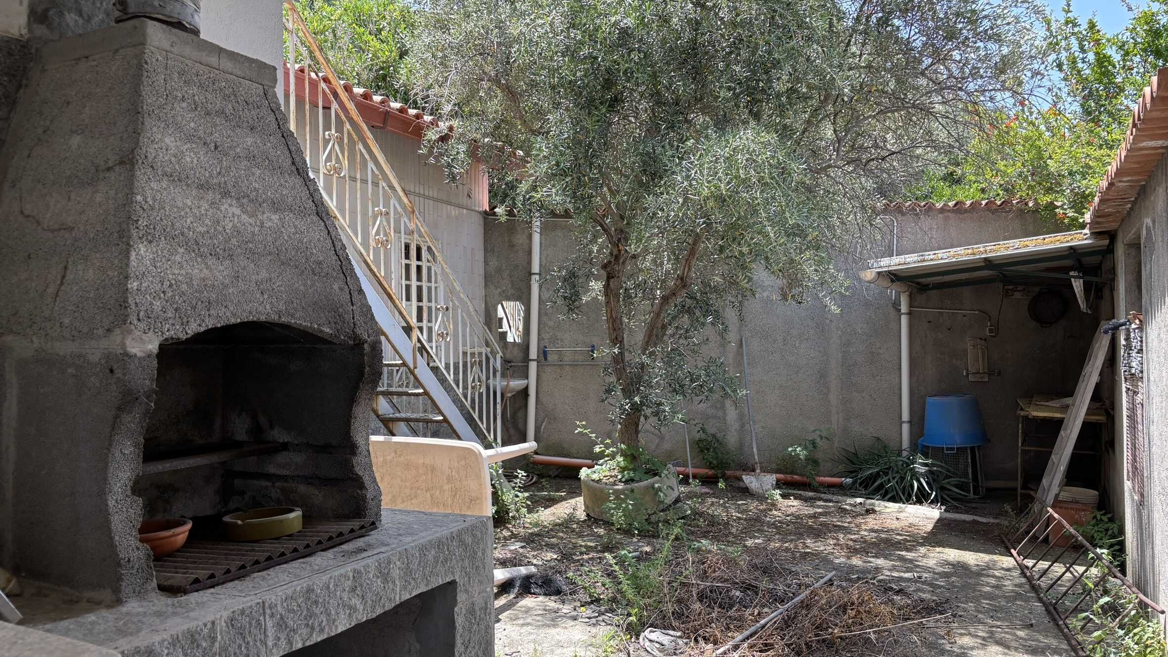 Forno da barbecue in pietra all'aperto in giardino con area relax e piante, perfetto per vivere momenti di convivialità e outdoor house design. Reale ambiente di un cortile esterno.