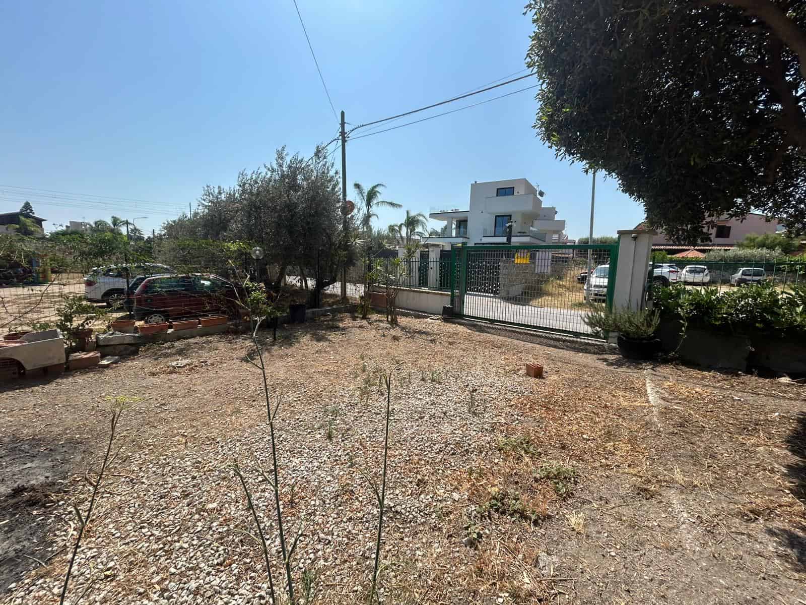 Spazio esterno di una proprietà residenziale con balcone in stile moderno, area di parcheggio e ampie aiuole con piante e alberi, ideale per investimenti immobiliari e offerte di case in vendita o in affitto.
