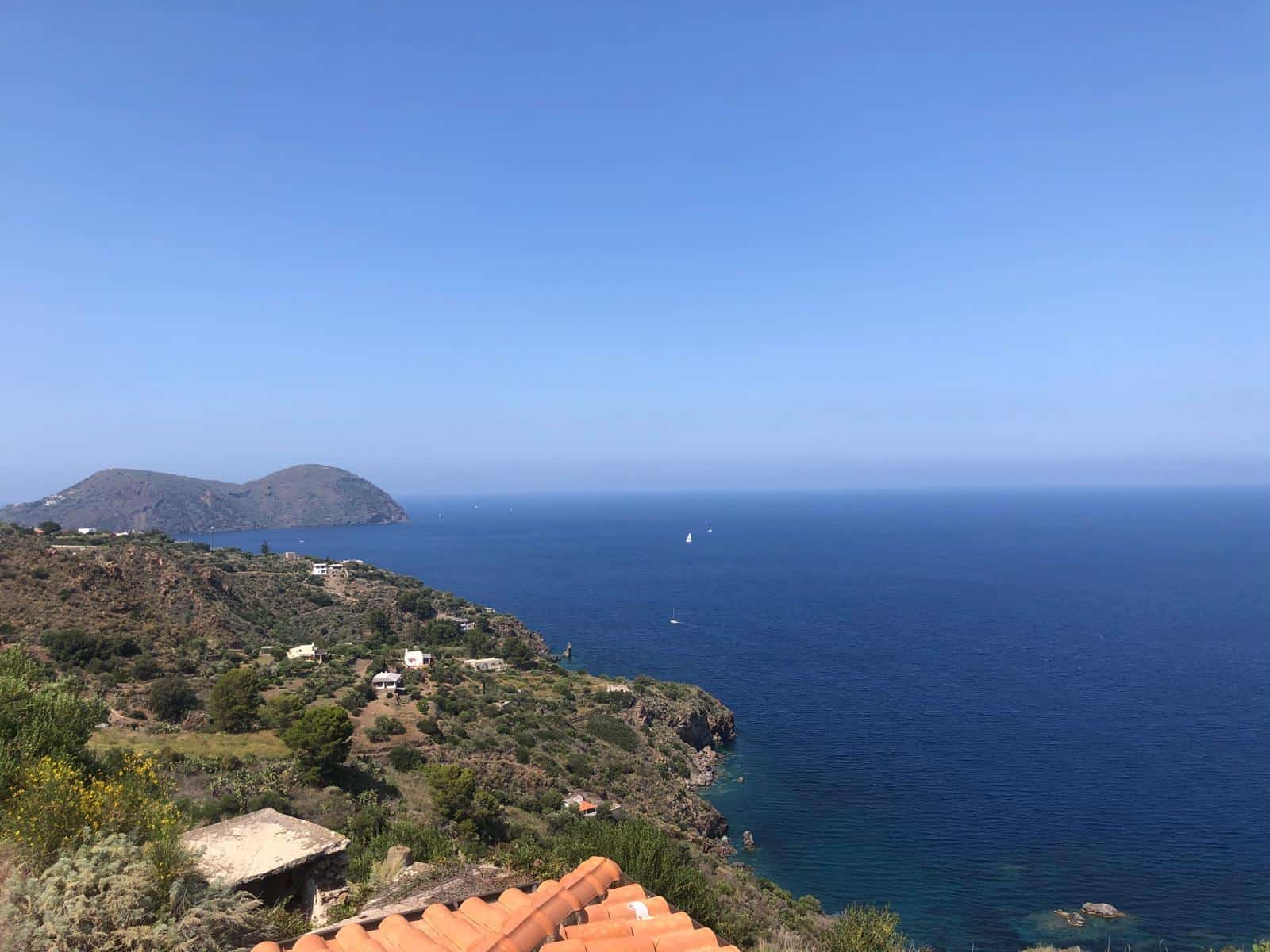 Vista mozzafiato sul mare e sulla costa con litorale roccioso, case panoramiche e colline verdi, ideale per immobili di lusso e investimenti immobiliari in località esclusive.