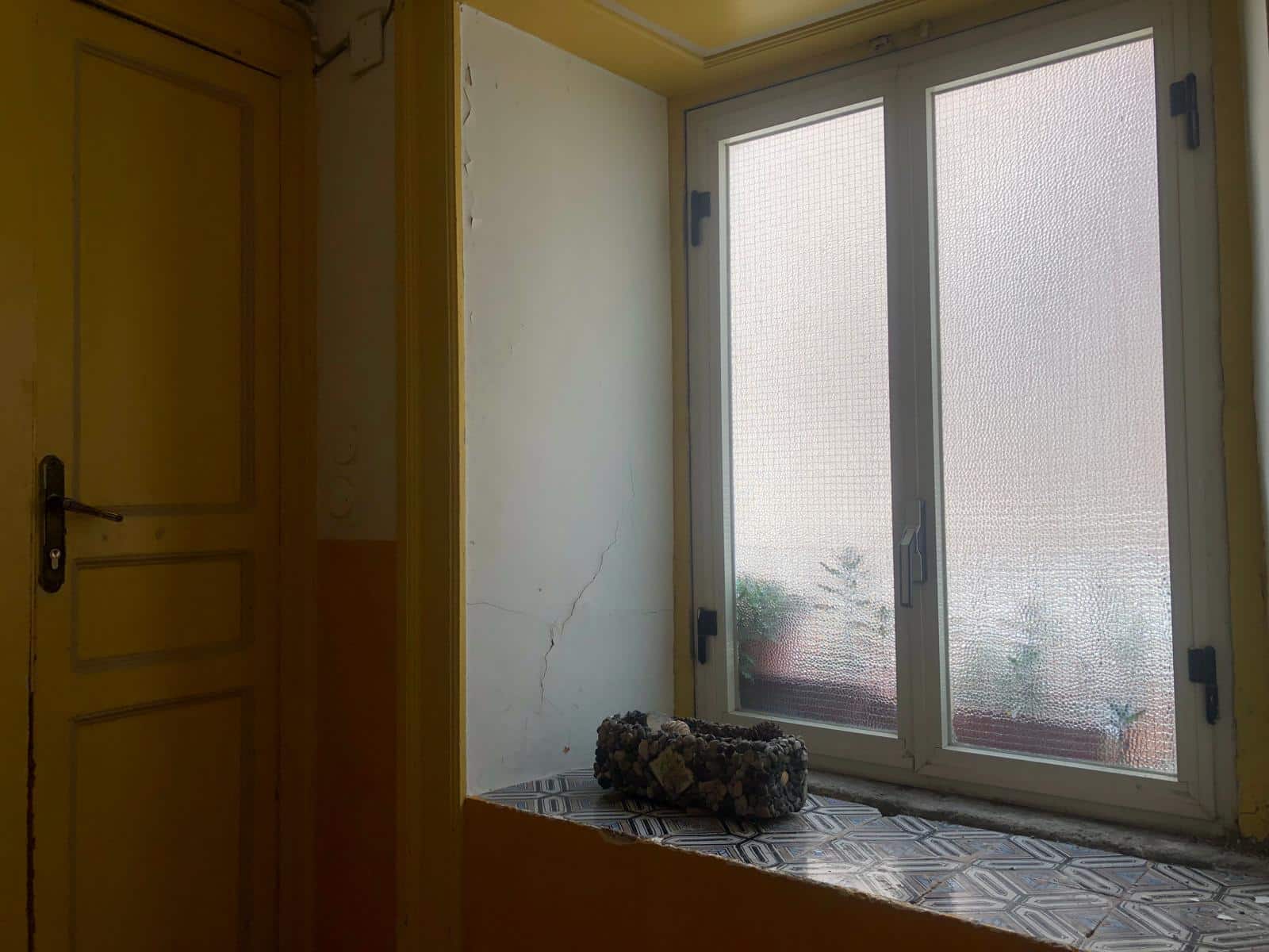 Finestra a doppia anta con vetro smerigliato in una cucina o soggiorno in stile tradizionale, con finestra decorativa, blocco di pietre e pareti con crepe, funzionale e di charme.