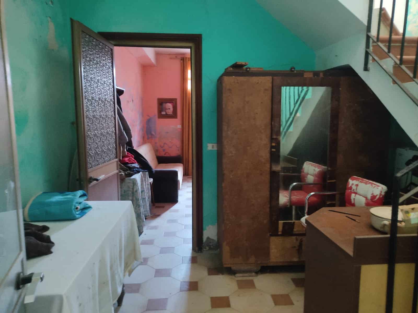Vecchio appartamento con arredi vintage in stile classico, pareti colorate e mobili d’epoca, ambiente accogliente e da ristrutturare, perfetto per chi ama il carattere dell’arredamento vintage.