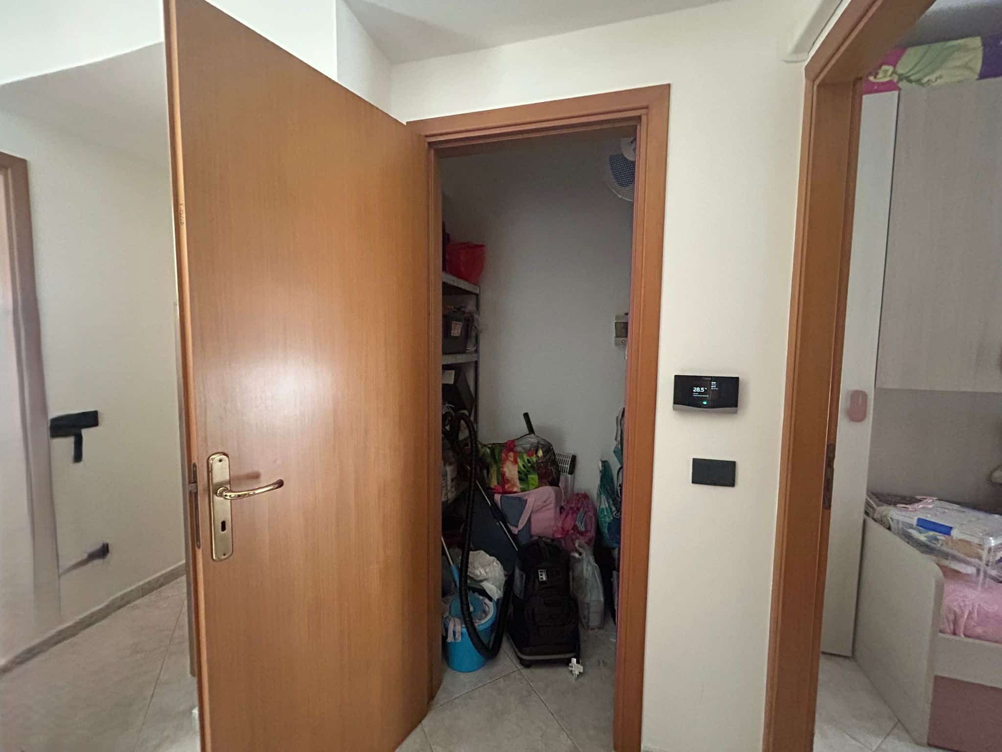 Ripostiglio in casa con armadio aperto, capiente e ordinato, contenente scatole, attrezzature e prodotti per la casa, atmosfera domestica e funzionale.