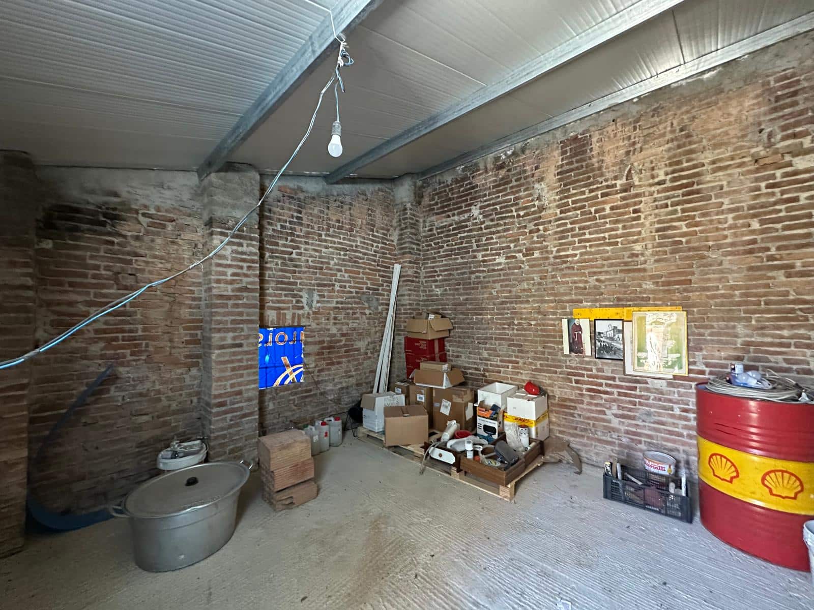 Vecchio magazzino o garage ristrutturato con pareti in mattoni a vista, pallet, scatole e contenitori per stoccaggio, ideale come spazio di deposito o atelier artigianale.