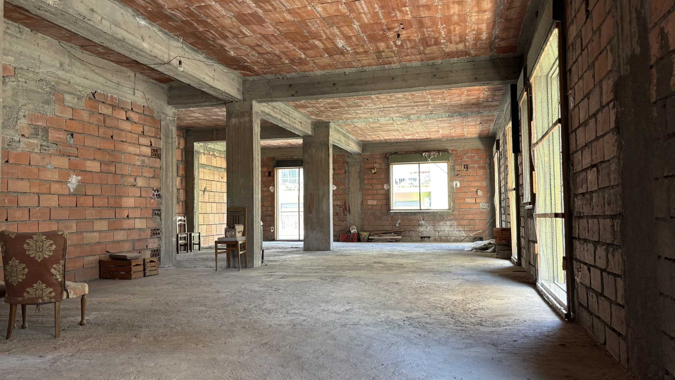Parete interna di un appartamento in fase di ristrutturazione, con murature in mattoni a vista e strutture portanti in cemento armato, pronta per la fase di finitura.