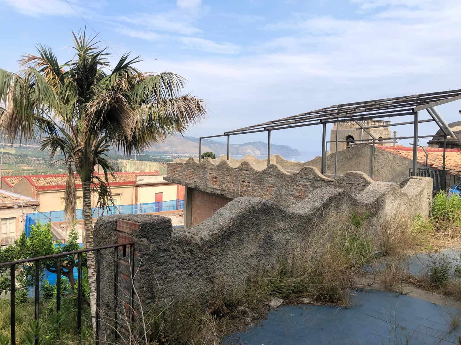Faro con vista sul mare e tetto in costruzione, paesaggio urbano con montagne sullo sfondo, case con tetti rossi e ambiente naturale, vista panoramica di un quartiere islandese.