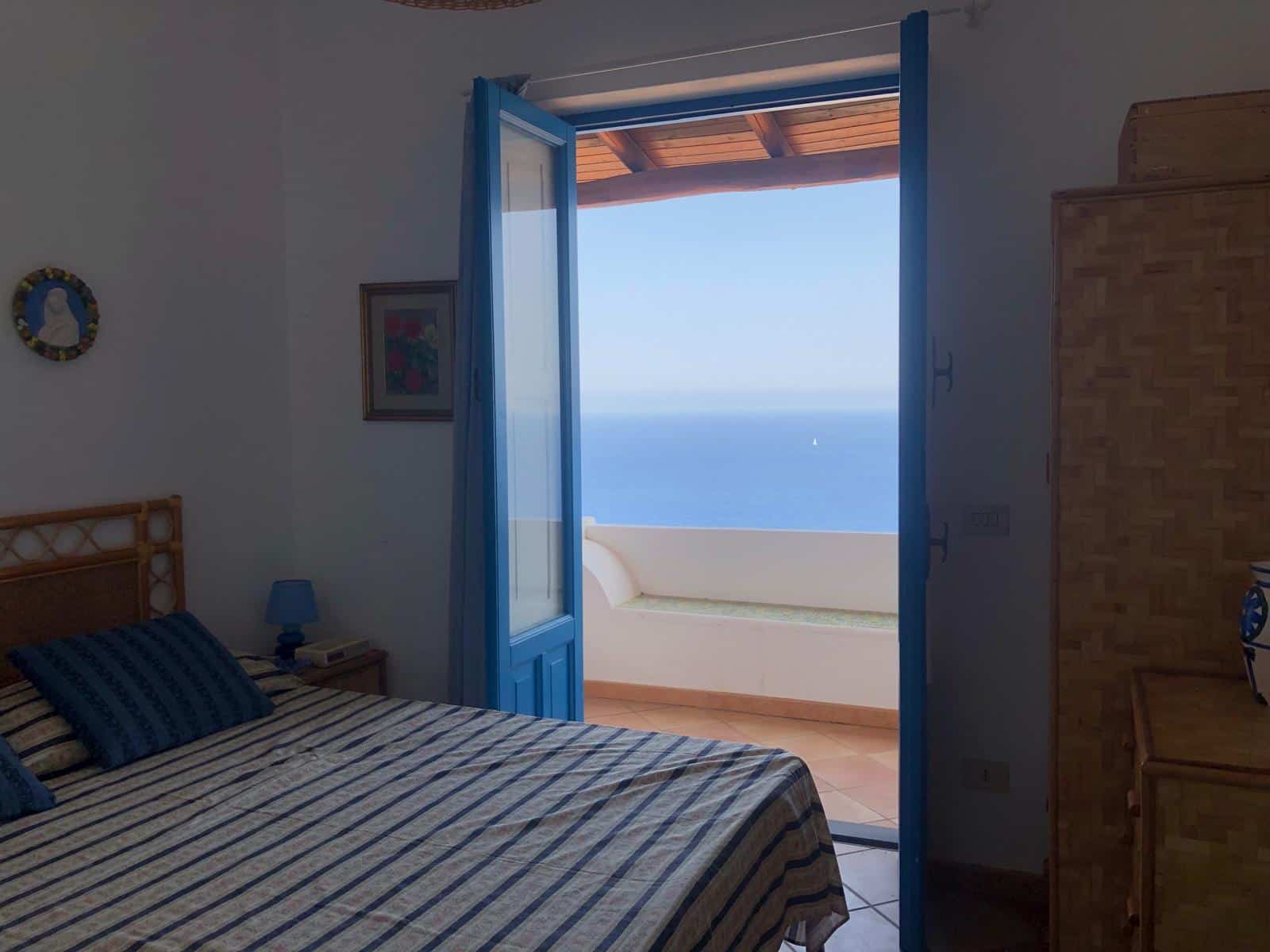Finestra con vista mare in stanza da letto, immagine di una casa vacanze al mare, arredamento in stile mediterraneo, ambienti luminosi, proprietà di NextCasa.