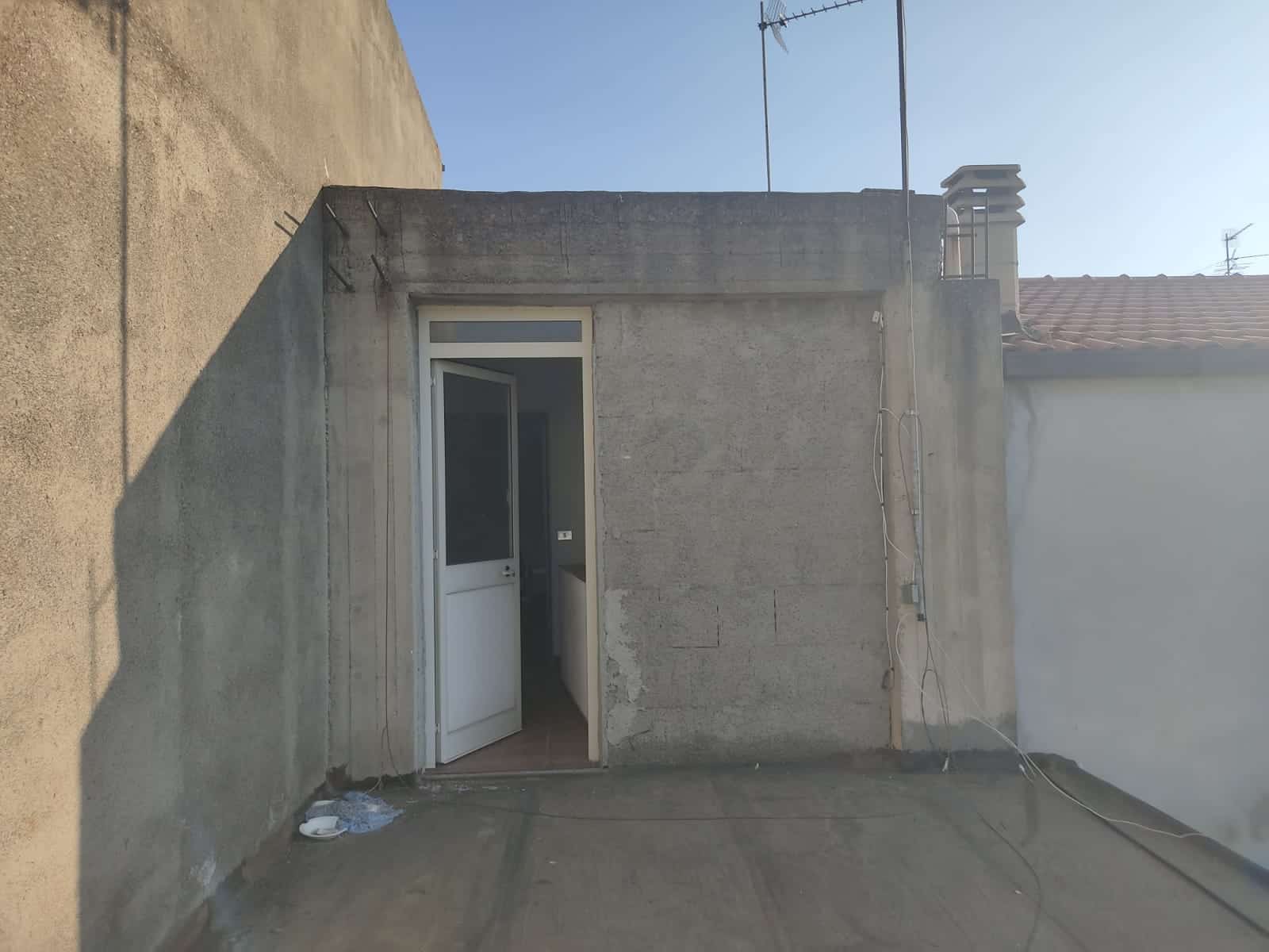 Finestra balconata su edificio in costruzione con pareti in cemento e accesso da porta finestra bianca, progettata per ambienti residenziali moderni e funzionali.