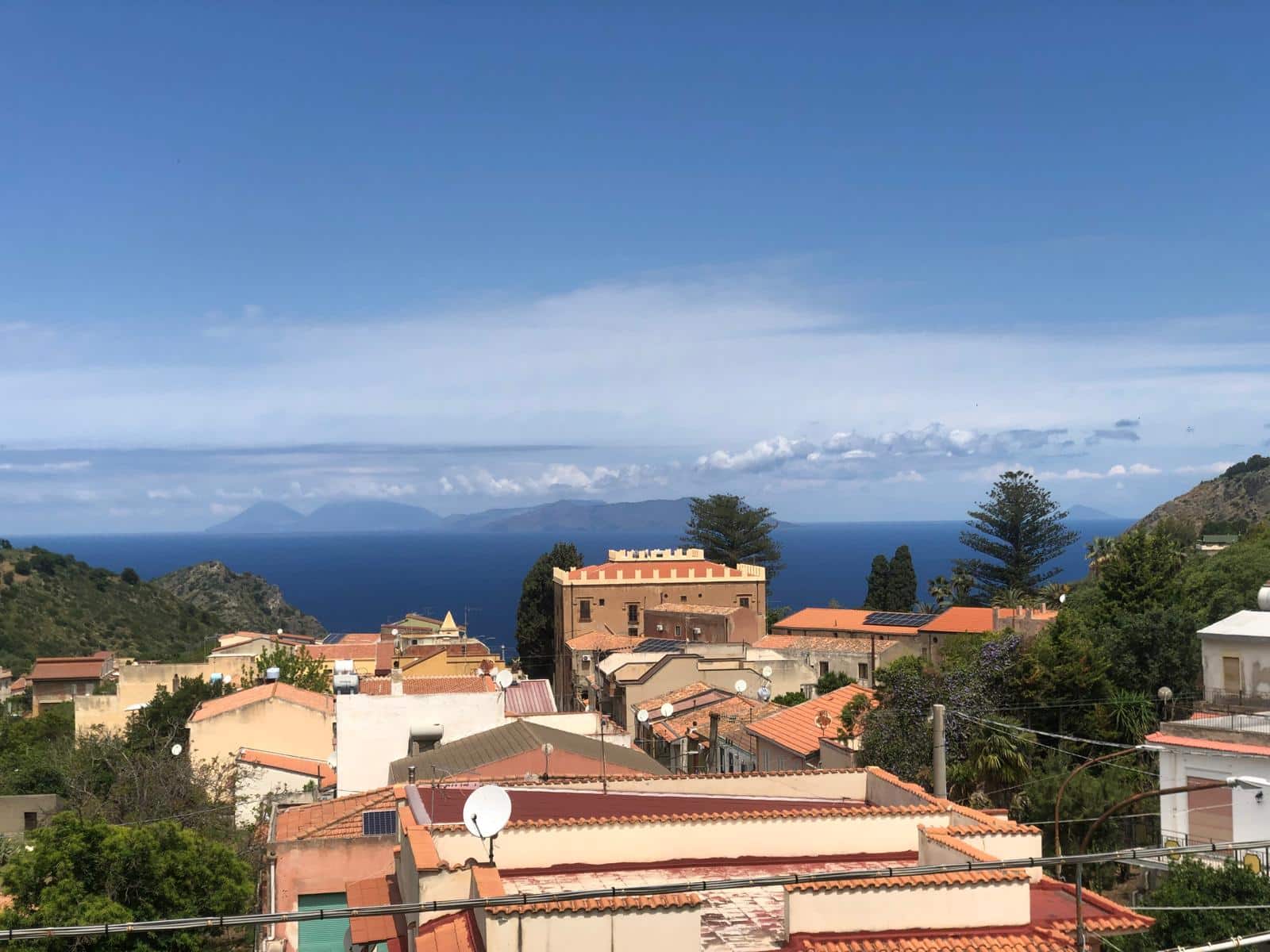 Vista panoramica delle case sul promontorio con il mare e le isole sullo sfondo, cielo sereno e verde paesaggio mediterraneo - immagine di alta qualità per annunci immobiliari NextCasa.