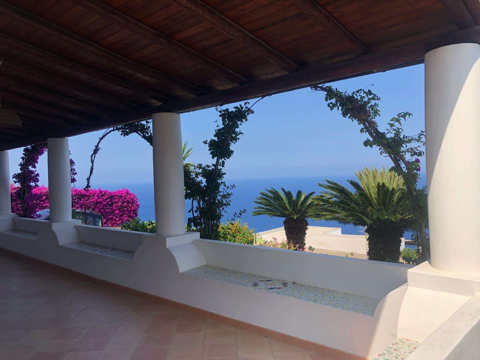 VISTA PANORAMICA MARE - Balcone di villa con vista incantevole sull'oceano, circondato da piante tropicali e fiori colorati, perfetto per relax e momenti di convivialità.