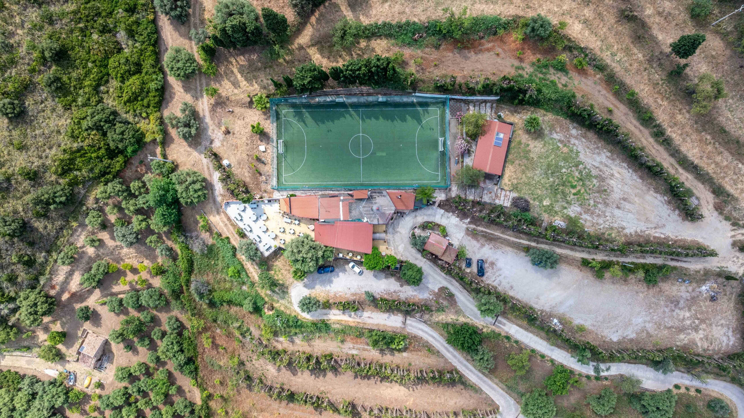 Campo da calcio all'aperto con panchine, area relax, strutture sportive e natura circostante, vista dall'alto dell'immobile NextCasa in Italia.