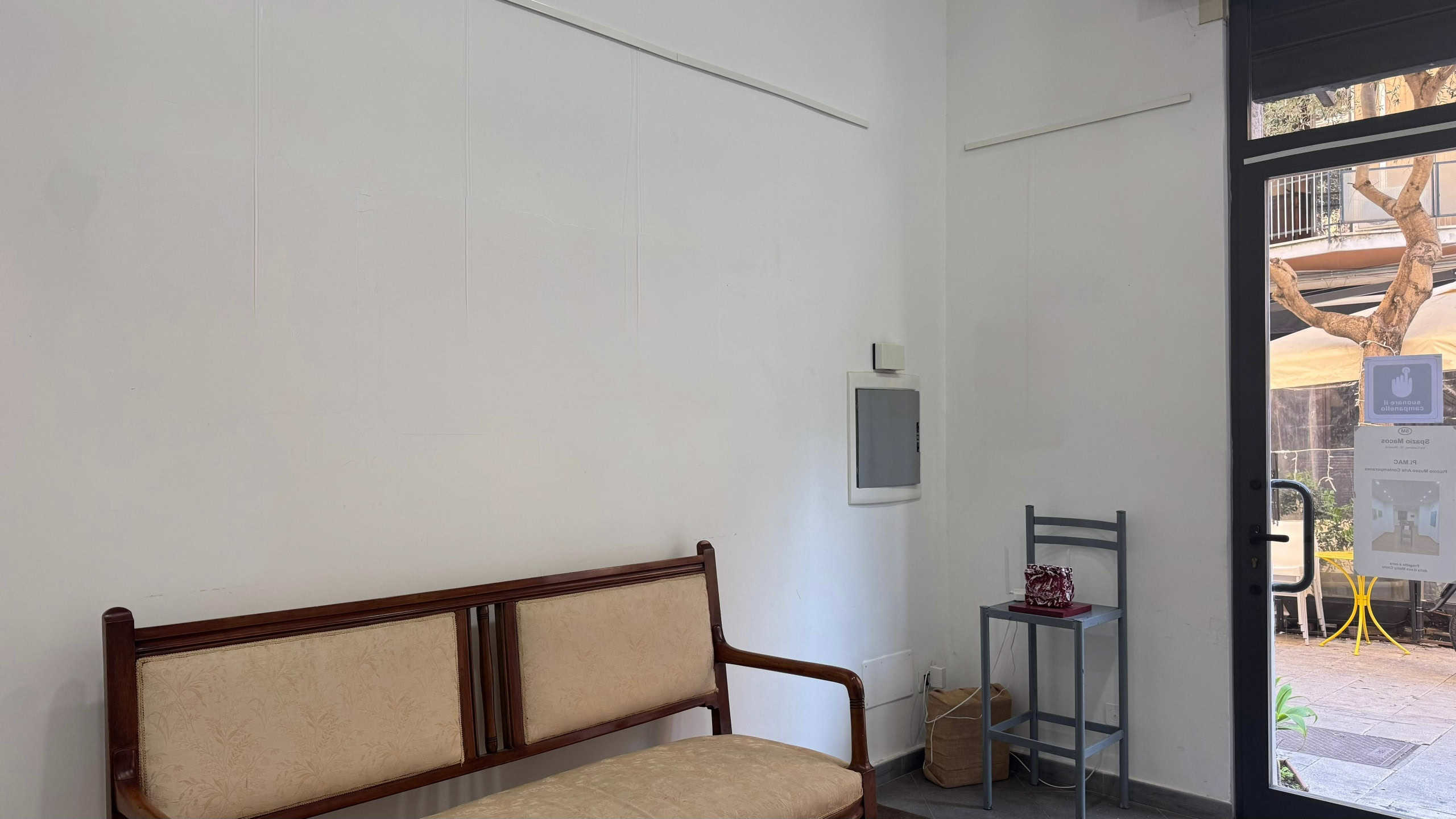Sedia in stile vintage e ingresso con vista su un cortile esterno, esempio di arredo minimalista per ambienti accoglienti e funzionali.