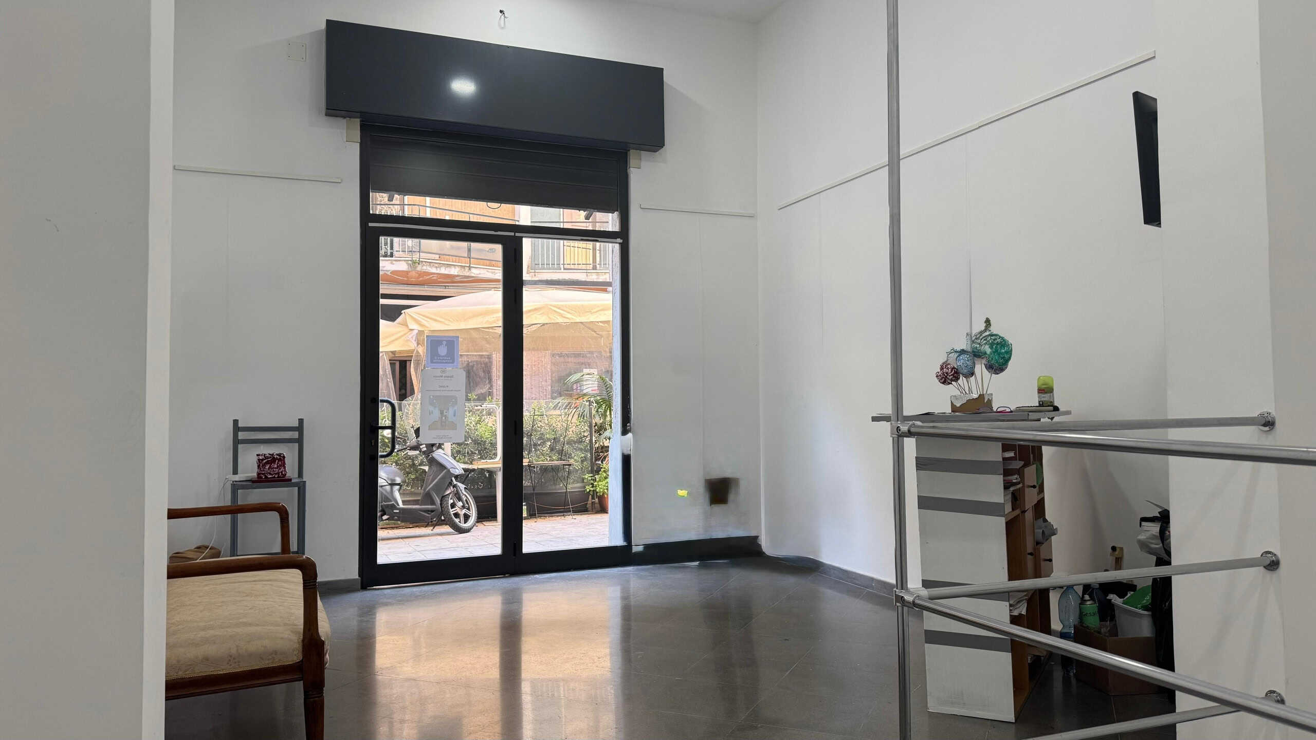 Moderno locale commerciale con vetrina e ingresso su strada, interno luminoso e spazioso, ottimo per attività professionali o negozi, con pareti bianche e arredi semplici.
