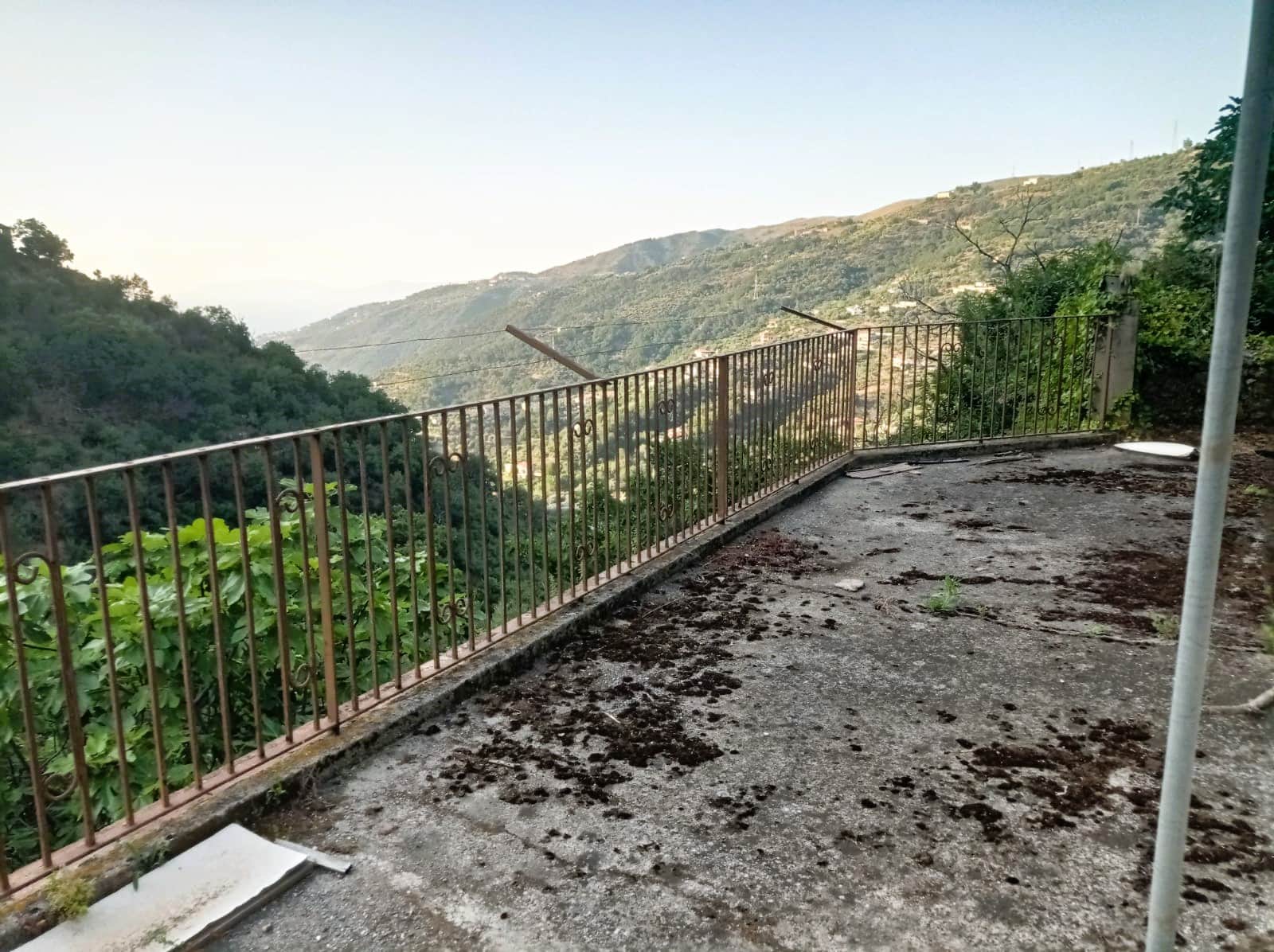 Balcone panoramico con ringhiera in ferro, vista sulle colline verdi e paesaggi naturali, ideale per relax e convivialità, in un contesto rustico e tranquillo.