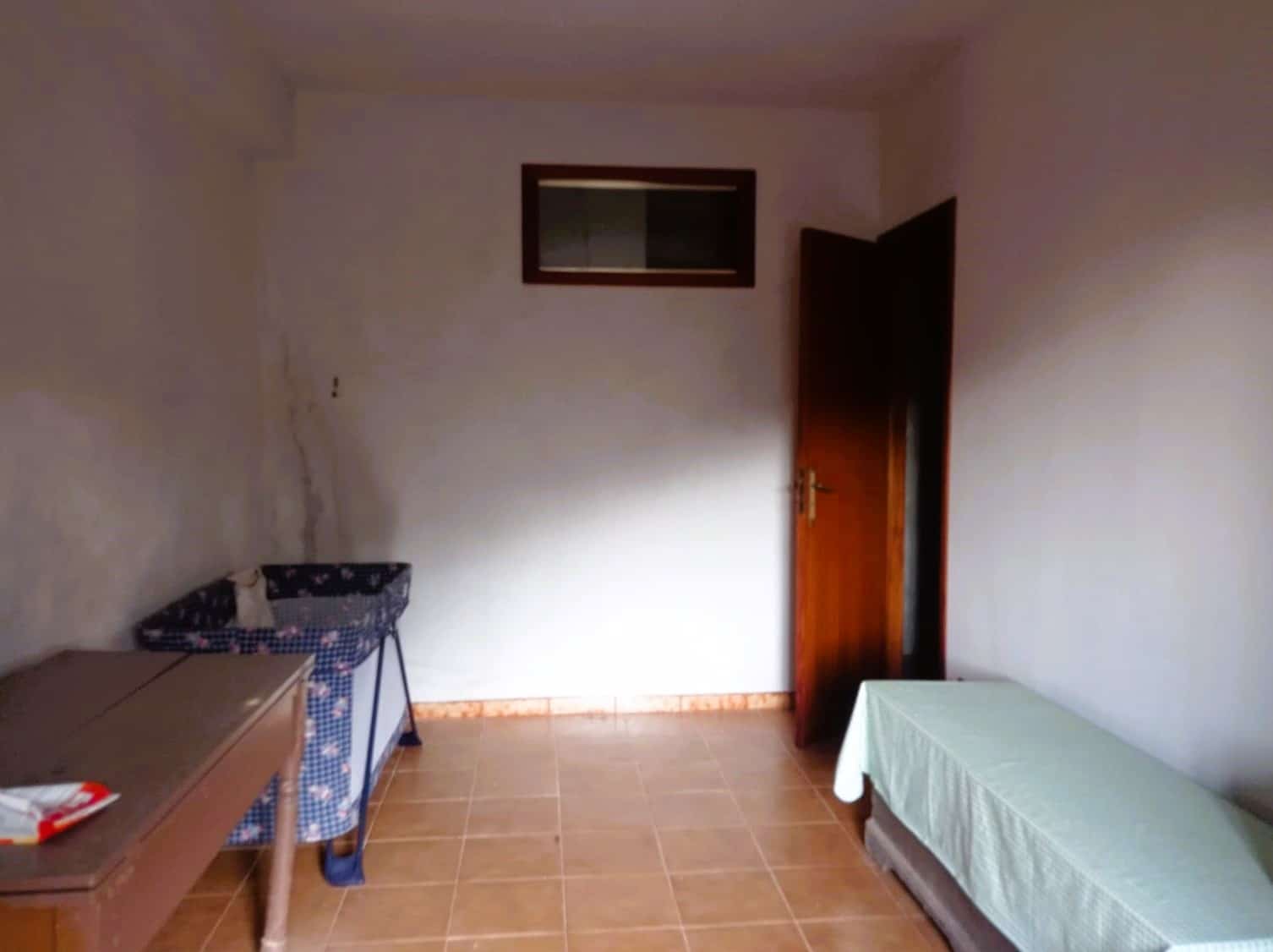 Soggiorno con letto singolo, armadio e mobili in stile semplice, pavimento in ceramica color naturale, pareti bianche, luce naturale, ambiente funzionale e adatto a soluzioni di affitto o abitazione temporanea.