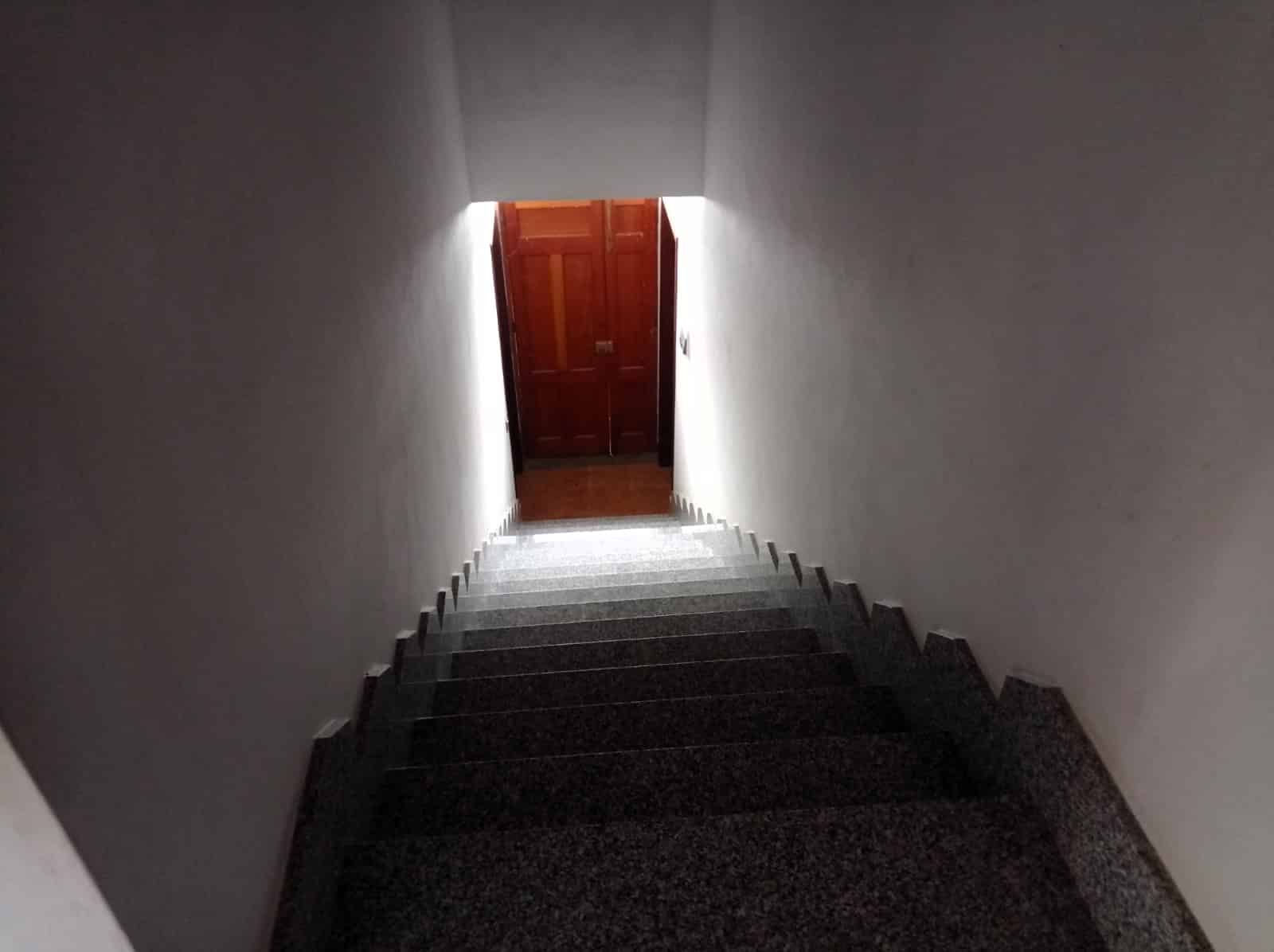 Scivolo al chiuso con pareti bianche e porta in legno, interno di un edificio, scala con gradini in pietra, design minimalista, illuminazione naturale, accesso all’ultimo piano, ambiente interno elegante, casa moderna, immobile in vendita, NextCasa.