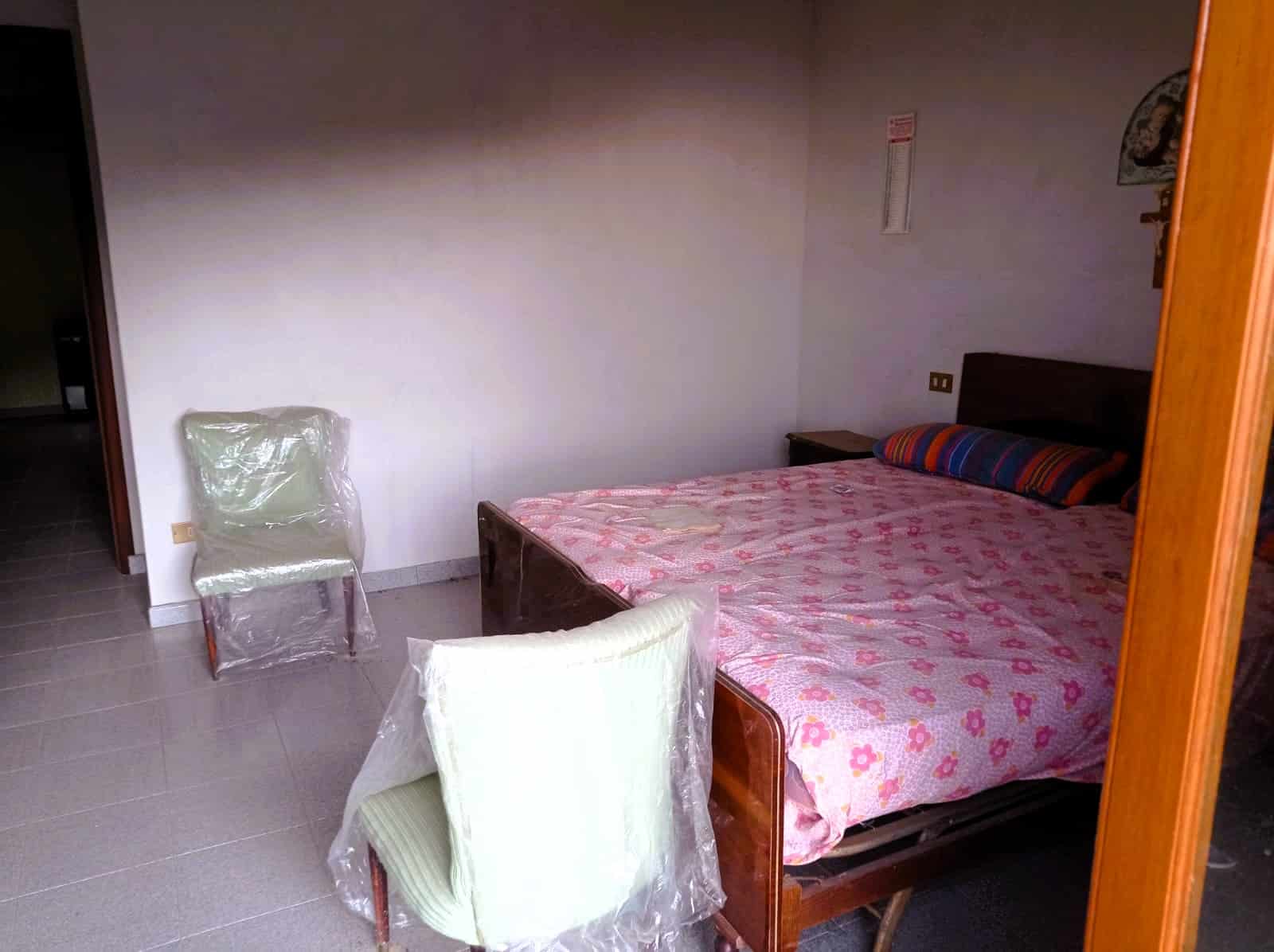Letto matrimoniale con copriletto rosa in una stanza arredata NextCasa, stile semplice e funzionale.
