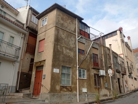 Rovine di edificio residenziale antico con pareti sgretolate e finestre con inferriate, situato in una strada di quartiere storico, rappresentativo di immobili da ristrutturare a Napoli.
