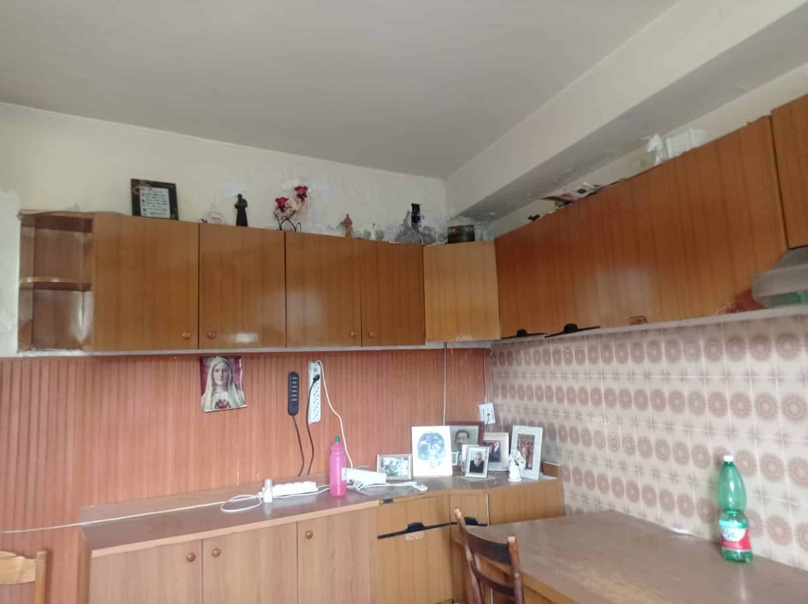 Armadio cucina in legno con parete decorata, ambiente abitativo autentico, mobili in stile vintage per casa accogliente e funzionale, dettagli di arredamento tradizionale italiano.