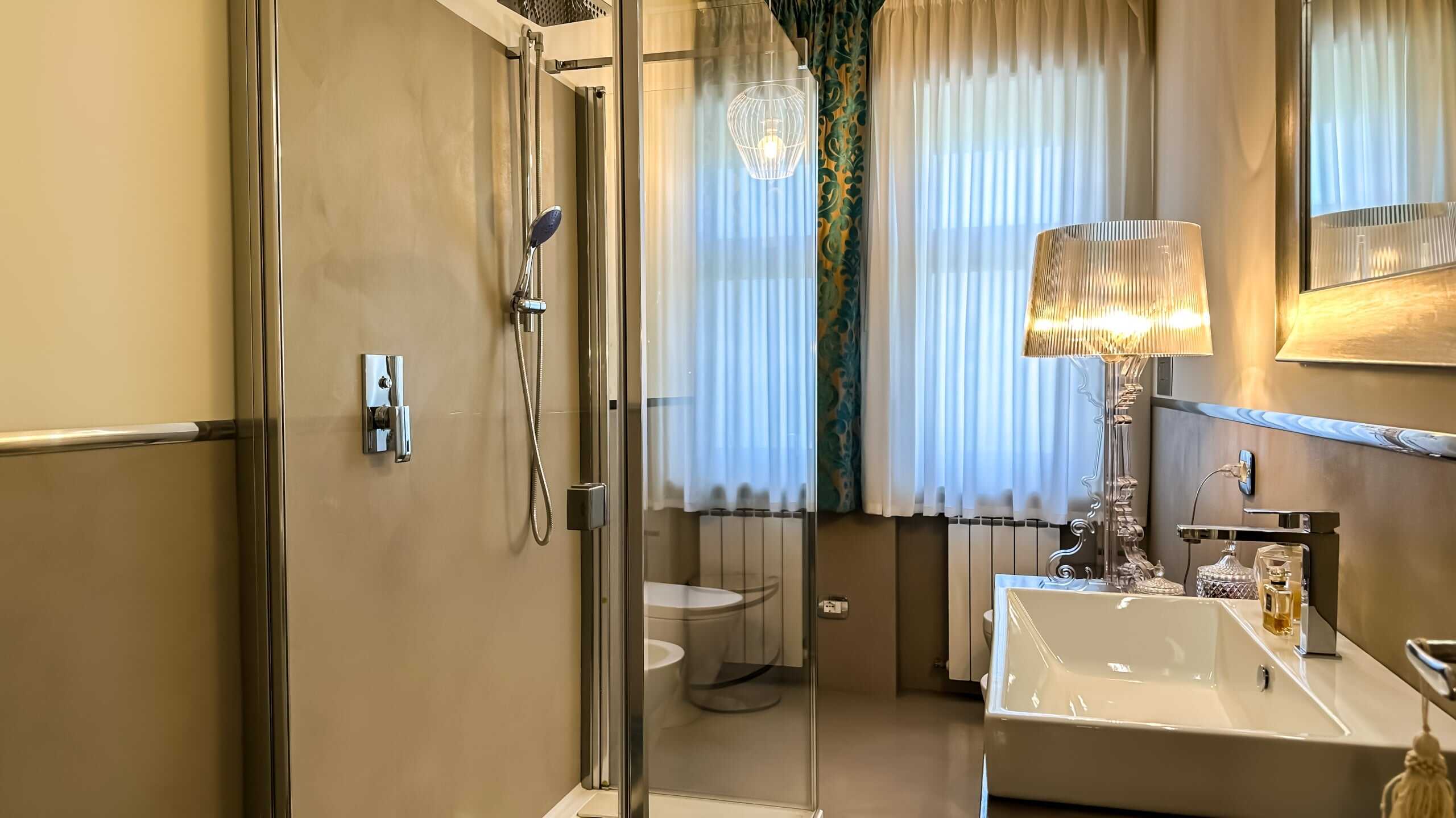 Bagno moderno con doccia walk-in, lavabo elegante e illuminazione soft, grandi tende bianche, dettagli di design e ambiente luminoso, ideale per residenze di lusso e affitti di alta qualità.