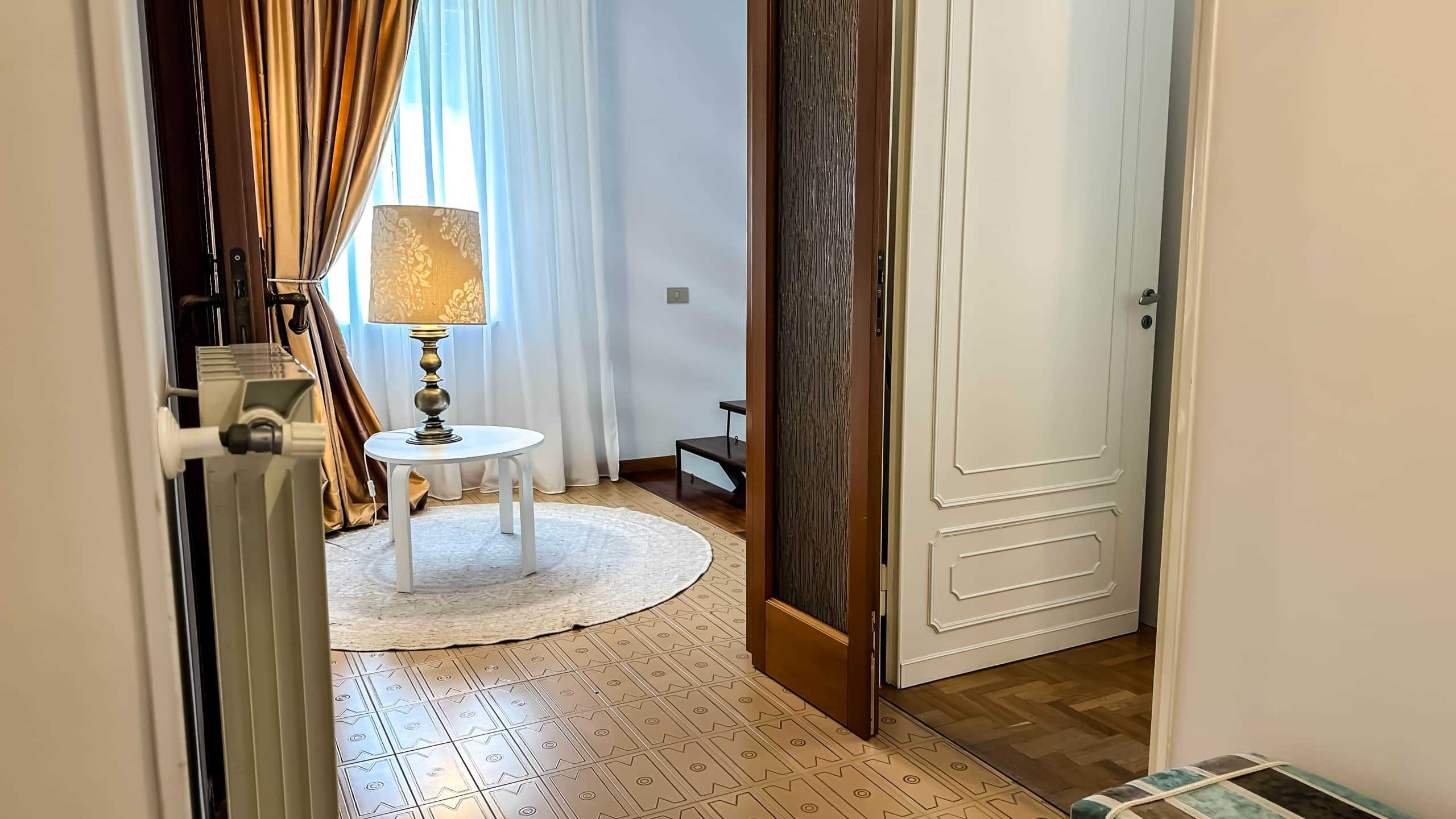 Immagine di un soggiorno elegante con tende dorate e luce calda da lampada, arredato con stile e attenzione ai dettagli, ideale per mostrare le proprietà di lusso disponibili tramite NextCasa.