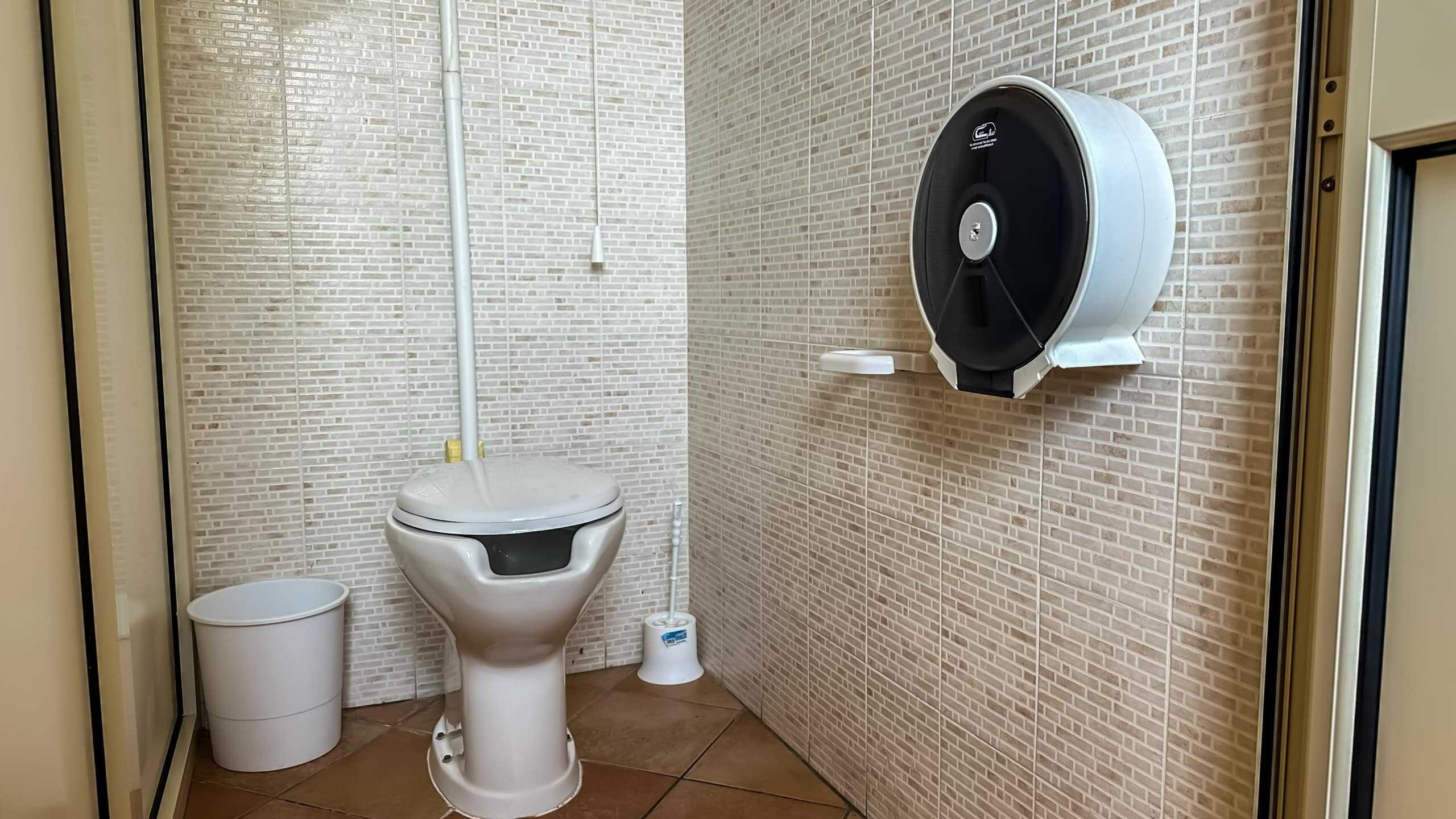 WC con tecnologia di asciugatura e igiene, servizio di pulizia professionale, sanitari moderni in ambienti commerciali, dotato di dispenser per salviette e bidet integrato, ideale per spazi pubblici e uffici NextCasa.
