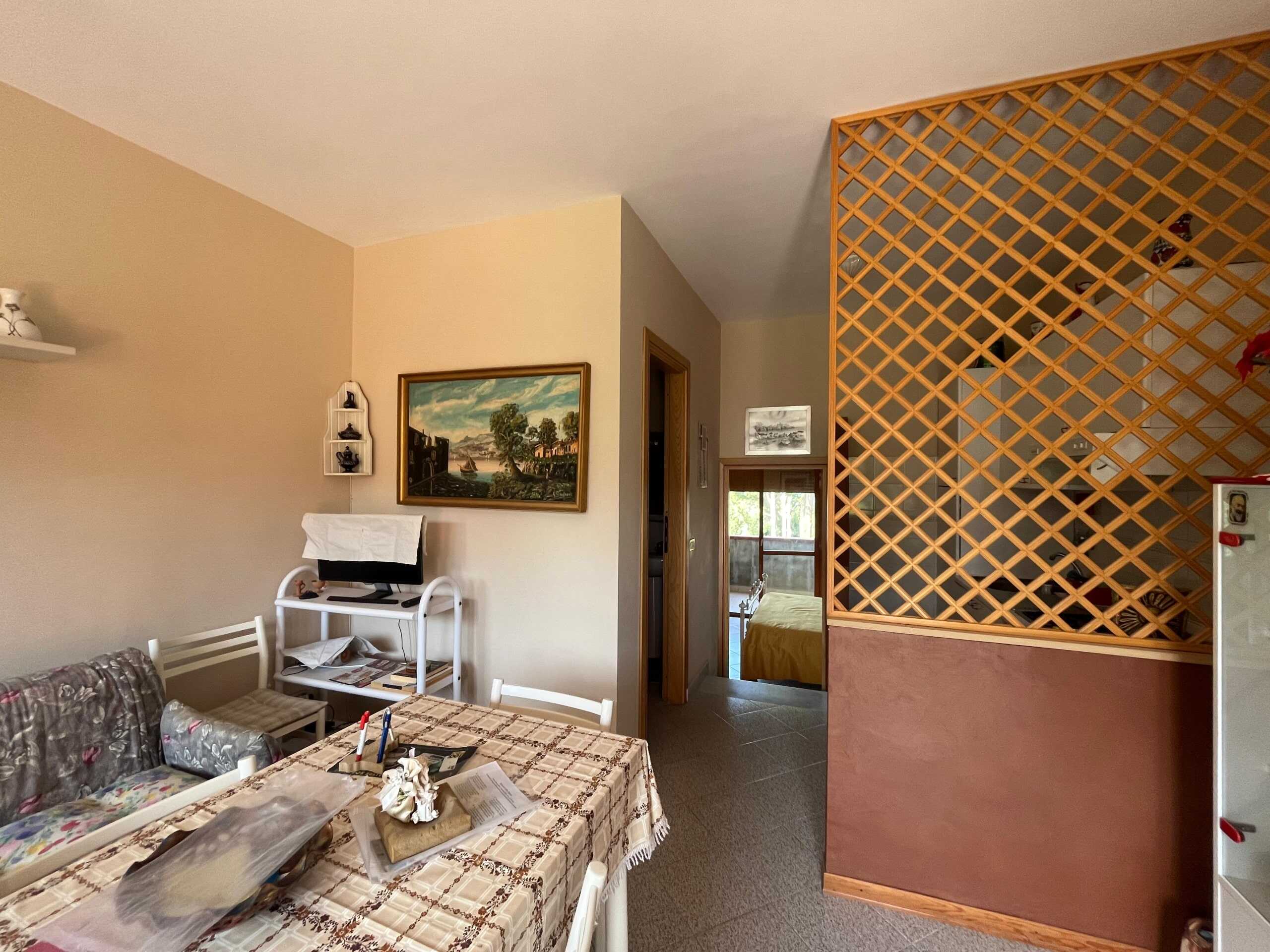 Piccolo appartamento arredato con zona living, tavolo da pranzo, parete divisoria in legno, camera da letto luminosa e elementi decorativi, ideale per affitto o investimento immobiliare.