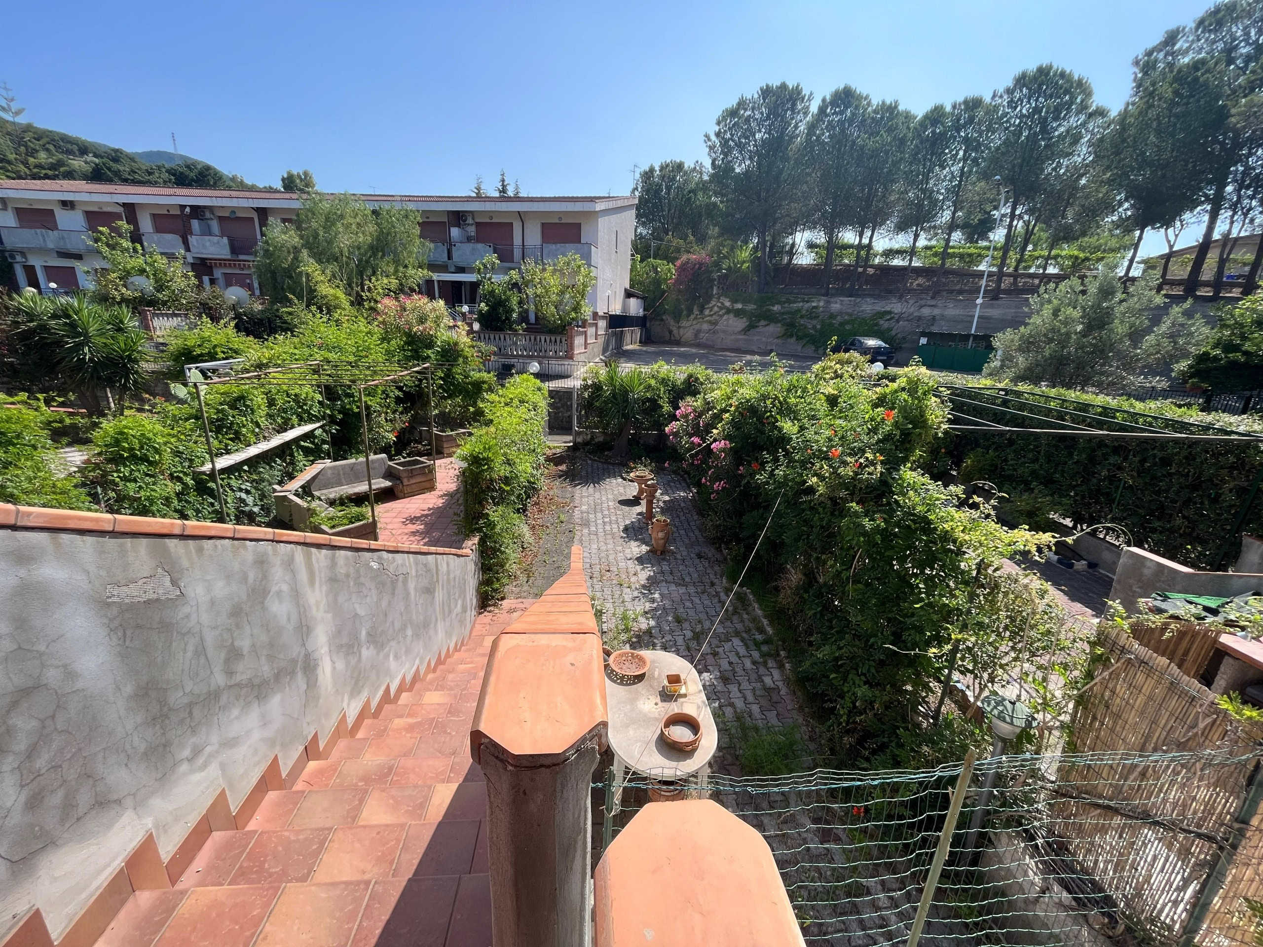 Giardino con panchine e piante verdi, vista dall'alto di un cortile residenziale con orto e ambiente tranquillo in zona urbana.