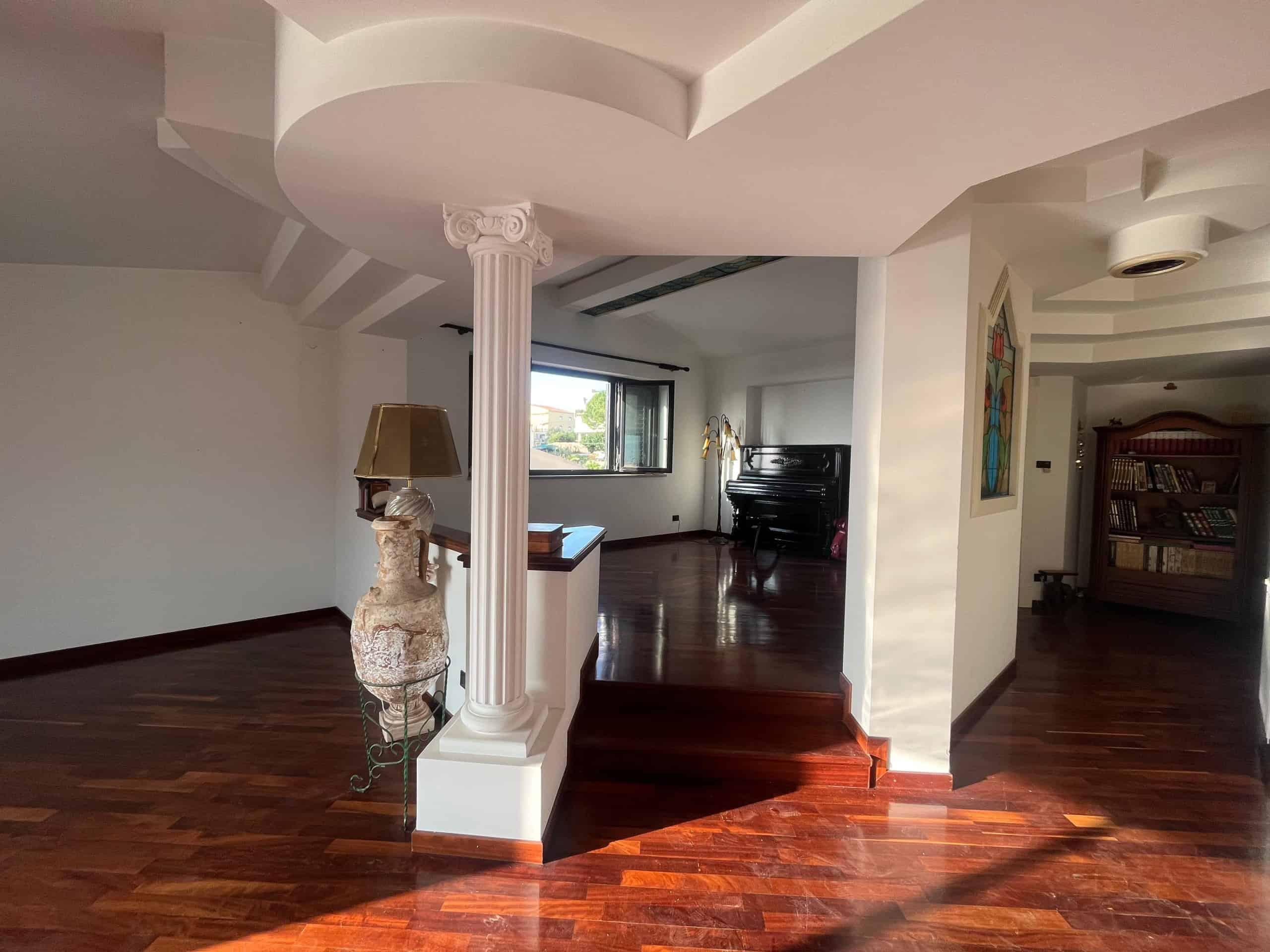 Rifacimento di interni con pavimenti in legno, colonne classiche e ampie finestre per ambienti luminosi e raffinati in una casa di design.