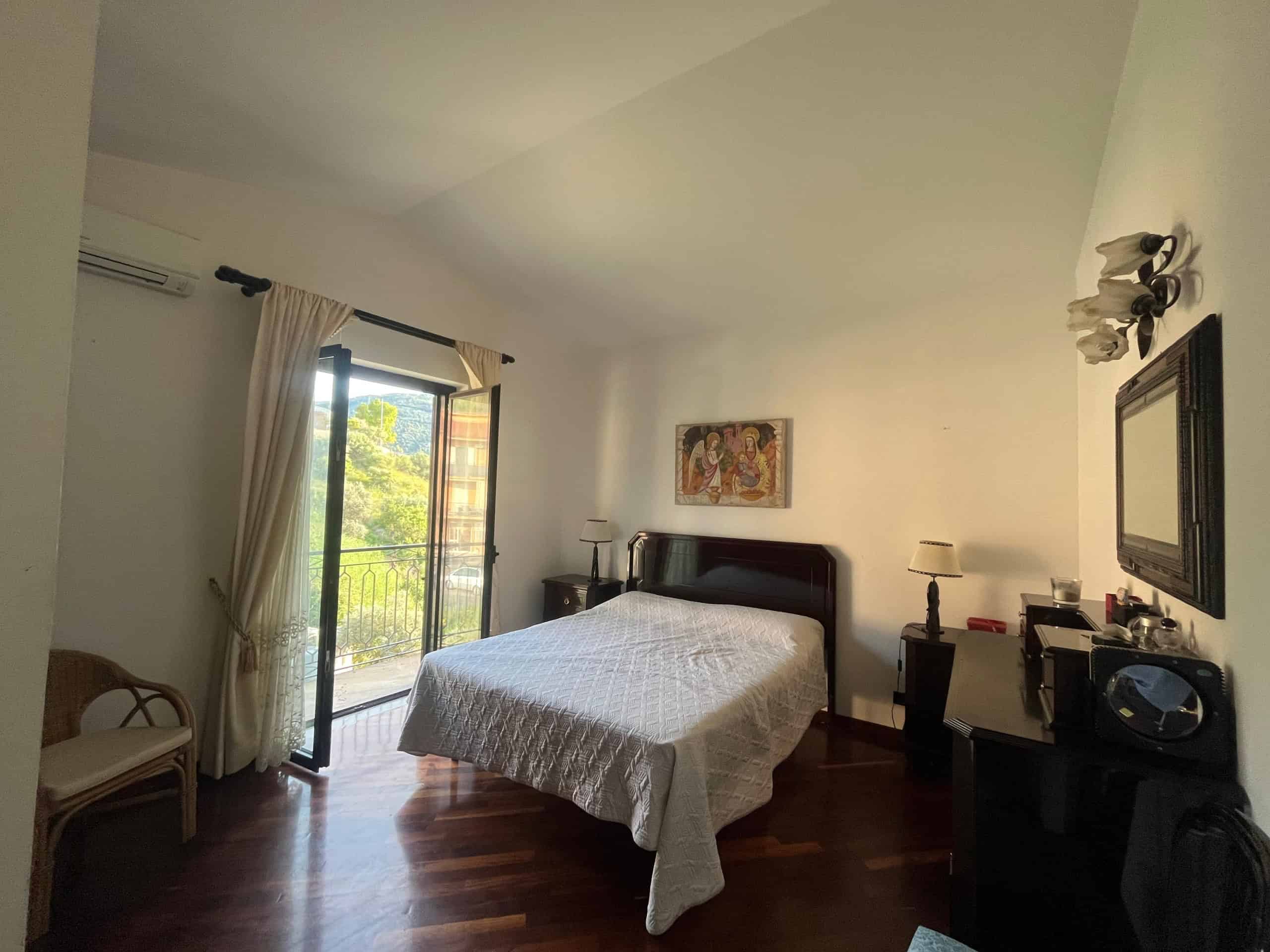 Camera da letto con balcone, arredi eleganti, letti e specchio, atmosfera luminosa, vista verde, ideale per case vacanza o residenza di charme.
