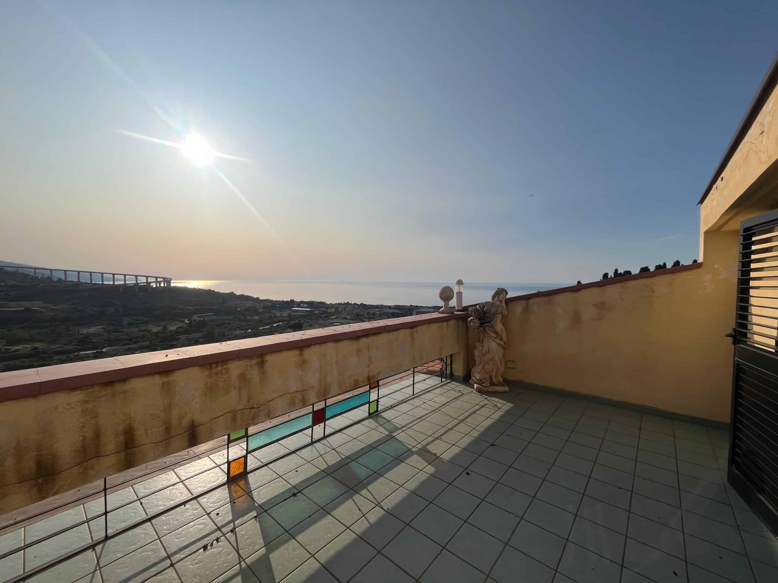 Vista panoramica dal balcone con vista mare, sole al tramonto, paesaggio mediterraneo e territorio collinare, ideale per case vacanza e proprietà di prestigio, location esclusiva a NextCasa.