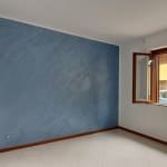 Vasto soggiorno con parete blu, finestra aperta sulla strada, ambienti luminosi, ottimo per immobili residenziali, arredo minimale, vista urbana, interno spazioso, ristrutturato, ventilato, ideale per affitti o acquisti immobiliari.