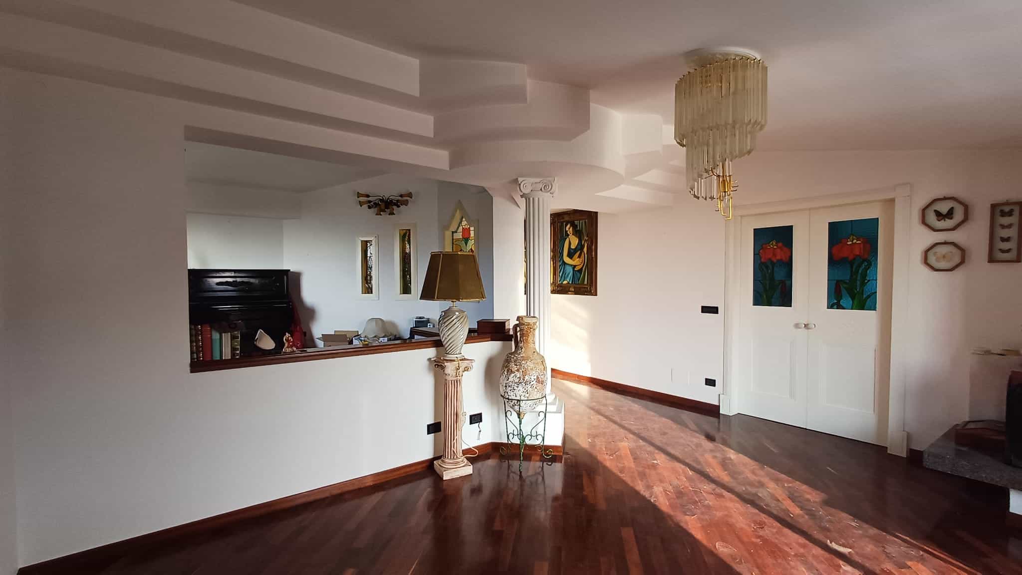 Vasta immagine di un soggiorno elegante e luminoso con pavimento in parquet, decori raffinati, opere d'arte e ampie vetrate che lasciano entrare molta luce naturale, ideale per famiglie e vendita immobiliare.