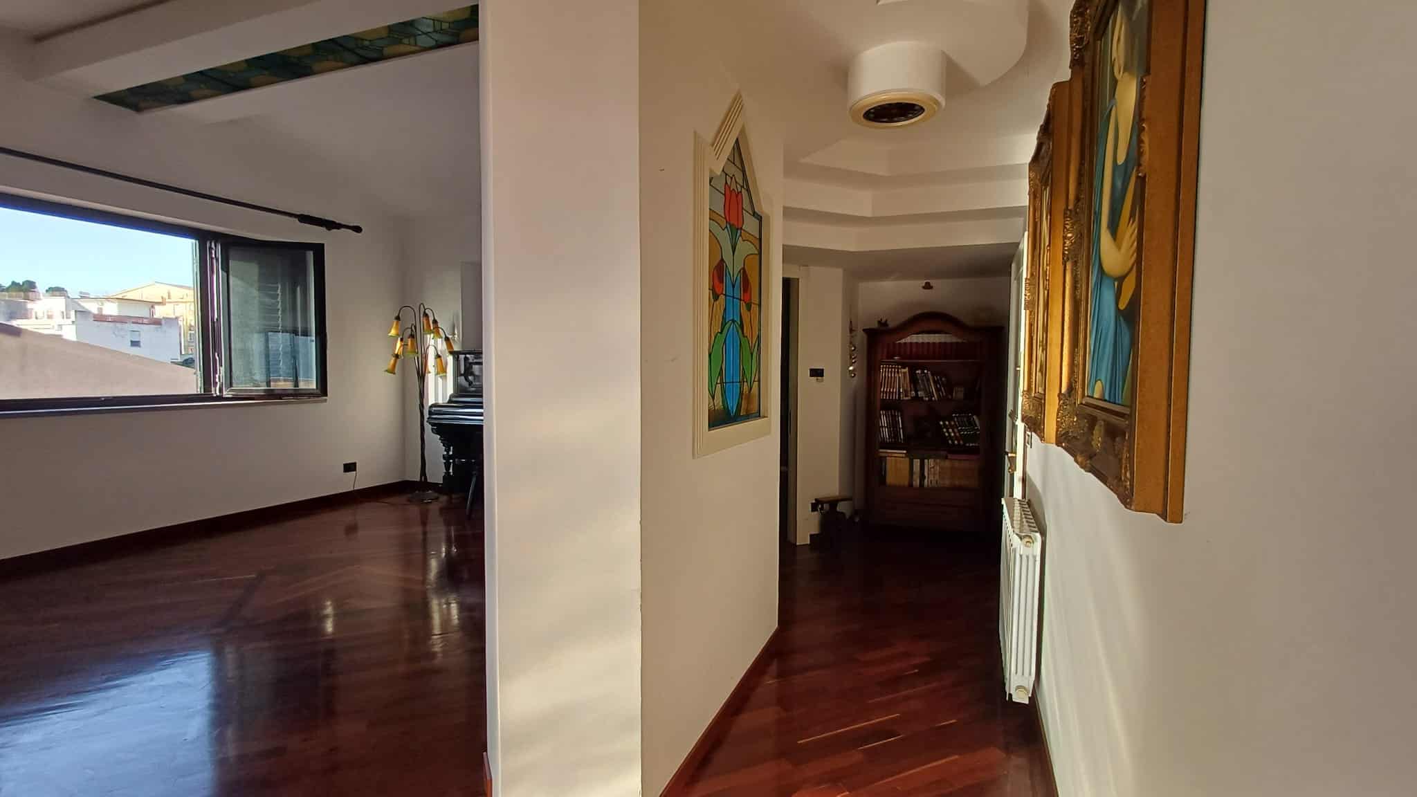 Finestra con vista urbana in appartamento di design con pareti decorate da opere d'arte e pavimento in parquet, ambiente luminoso e elegante, ideale per immobili di alta qualità.