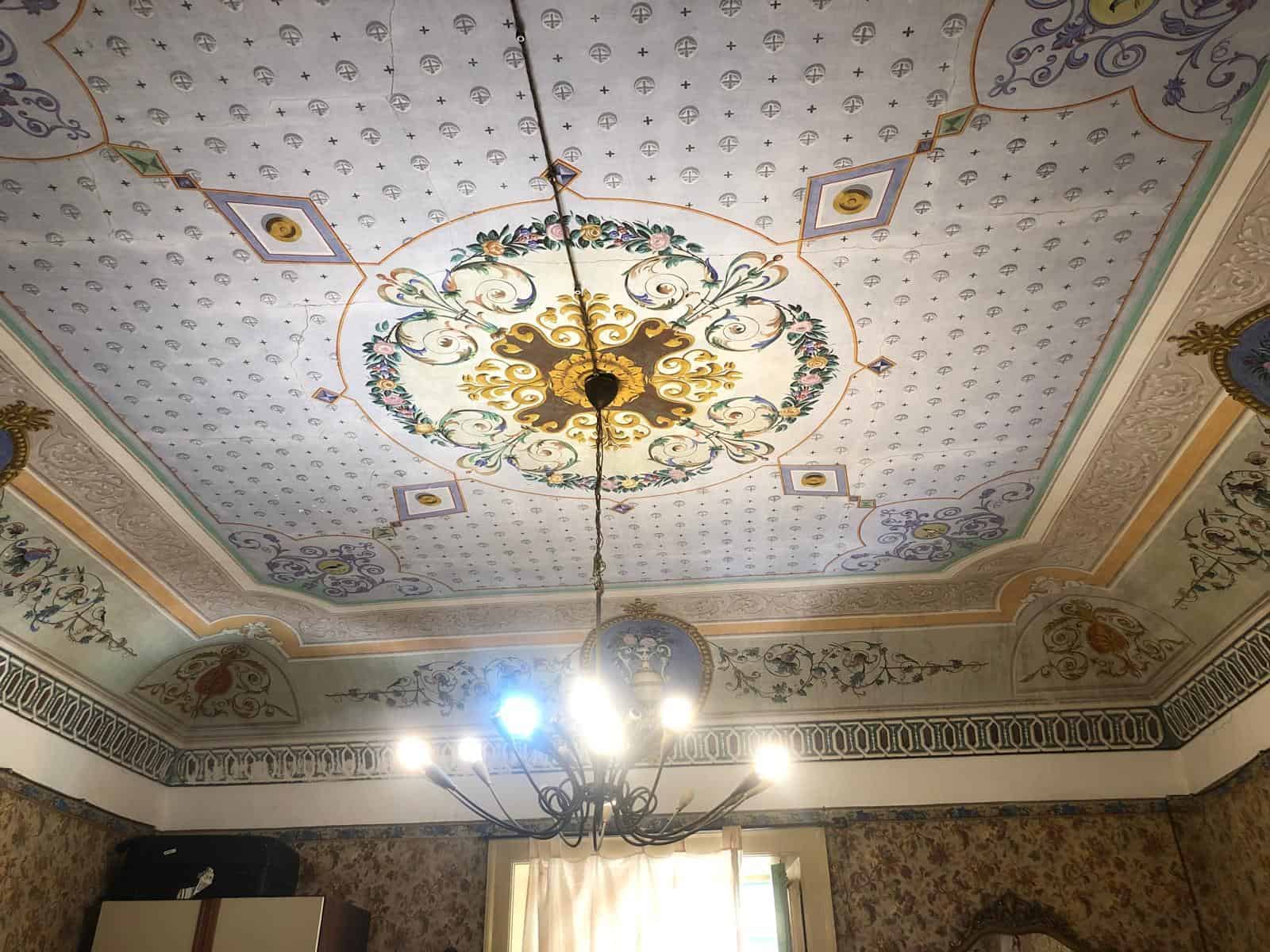 Elegante soffitto con affreschi artistici e chandelier in stile classico, perfetto per interni di lusso e design di alta qualità.