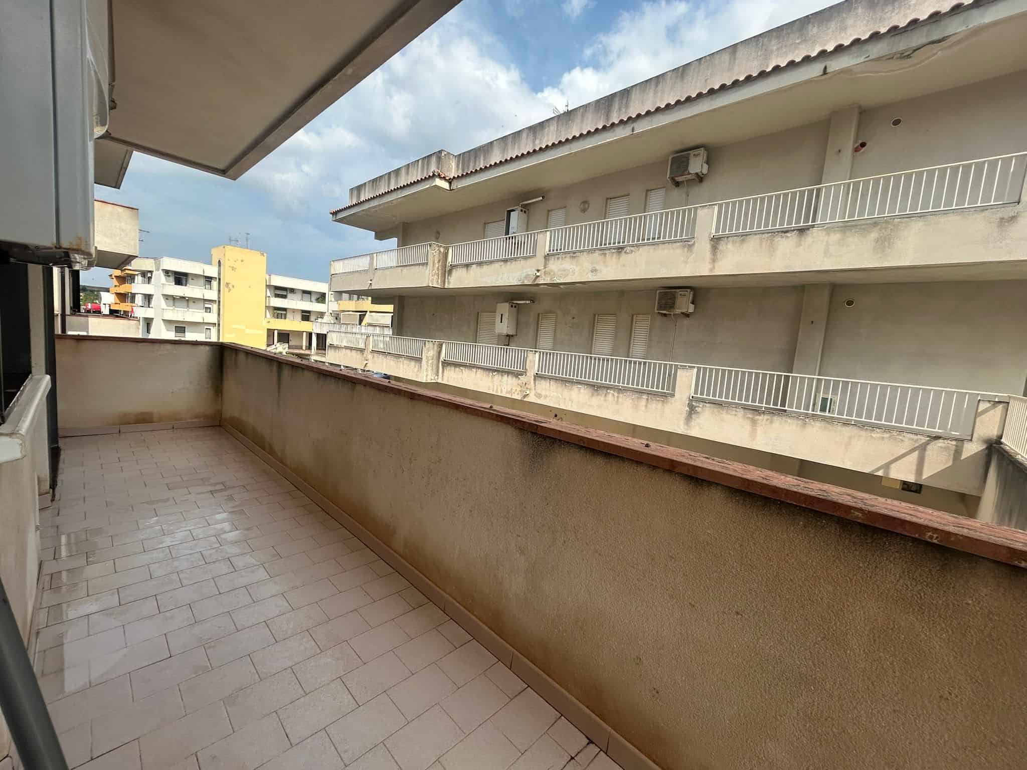 Balcone con vista su cortile condominiale, spazio esterno abitabile e zona relax, ideale per appartamenti in vendita o in affitto nel centro urbano.