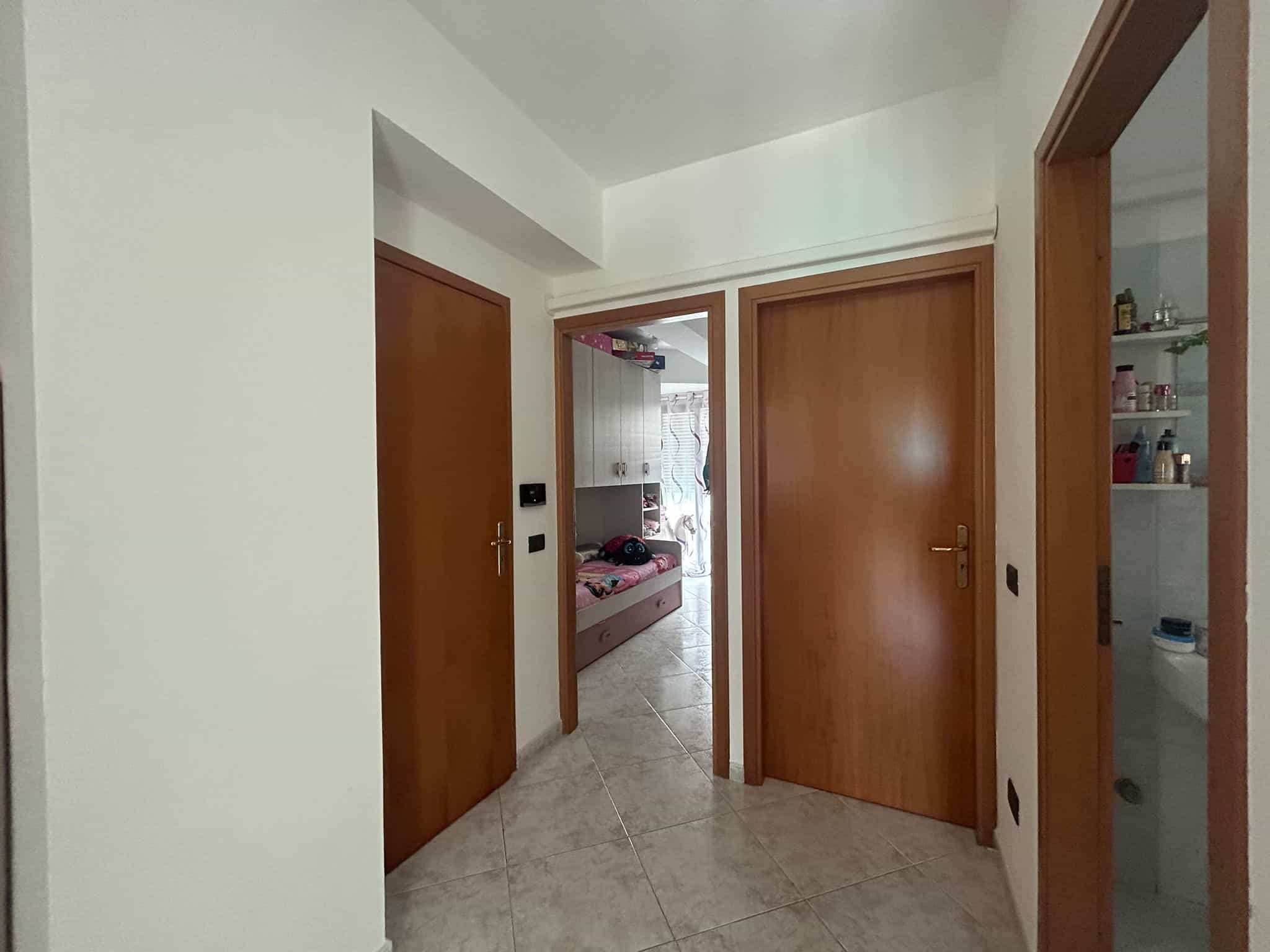 Scorcio di ingresso con porte in legno, vista sulle camere e bagno, ambiente accogliente e funzionale, perfetto per abitazioni moderne e confortevoli.