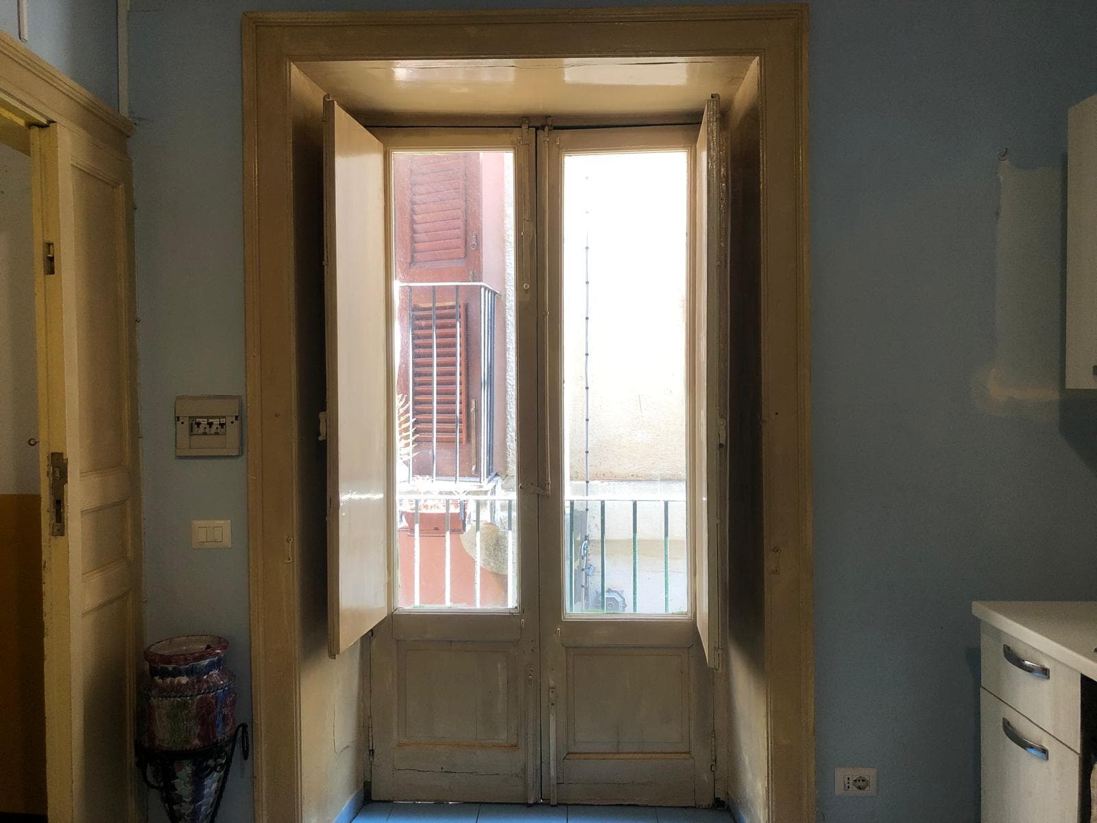 Balcone con porta finestra in legno, illuminazione naturale, vista su villetta, scanalature di vetro, infissi in legno, ambiente interno ampio e luminoso vasca e cucina moderna, luce naturale e dettagli di design.