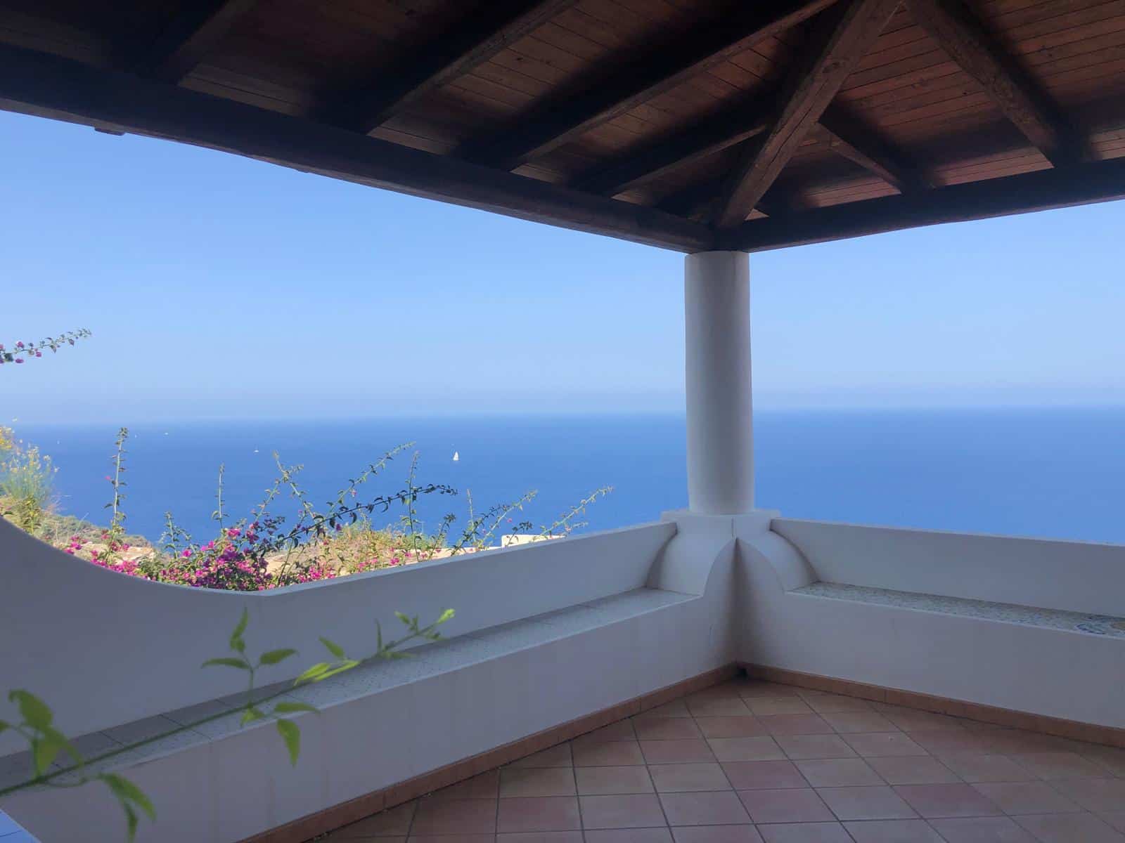 Vista panoramica mare dalla terrazza di una casa al mare con arredi moderni. Luogo ideale per relax e godersi il paesaggio marino e il cielo azzurro. Design minimalista e atmosfera serena per un soggiorno di lusso.