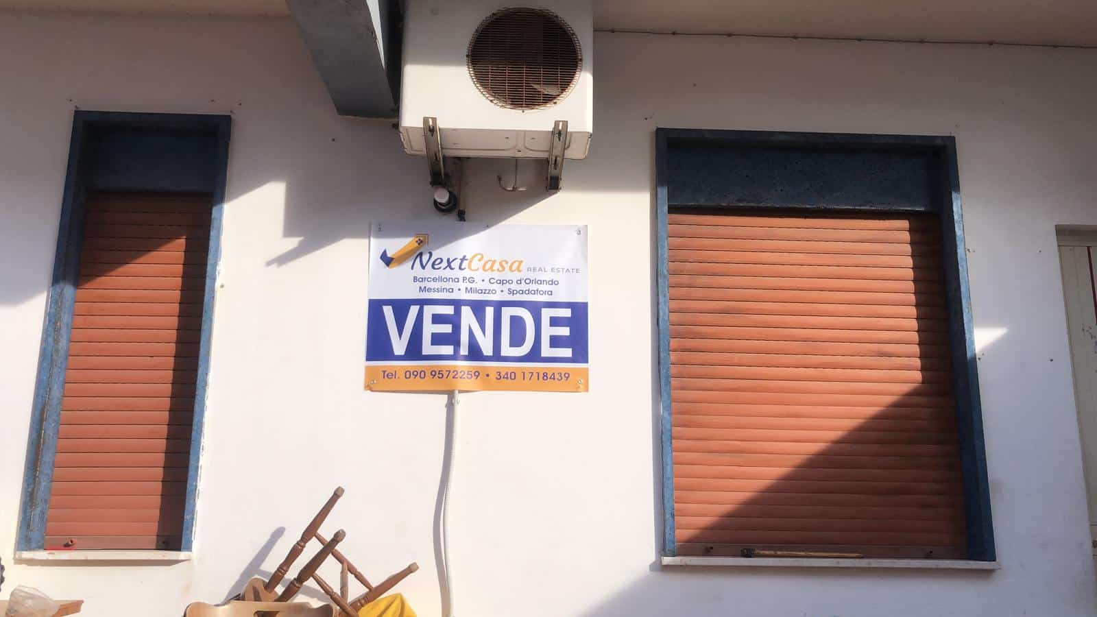 Vende immobile con serrande avvolgibili e condizionatore, segnale di vendita, opportunità immobiliare, NextCasa.