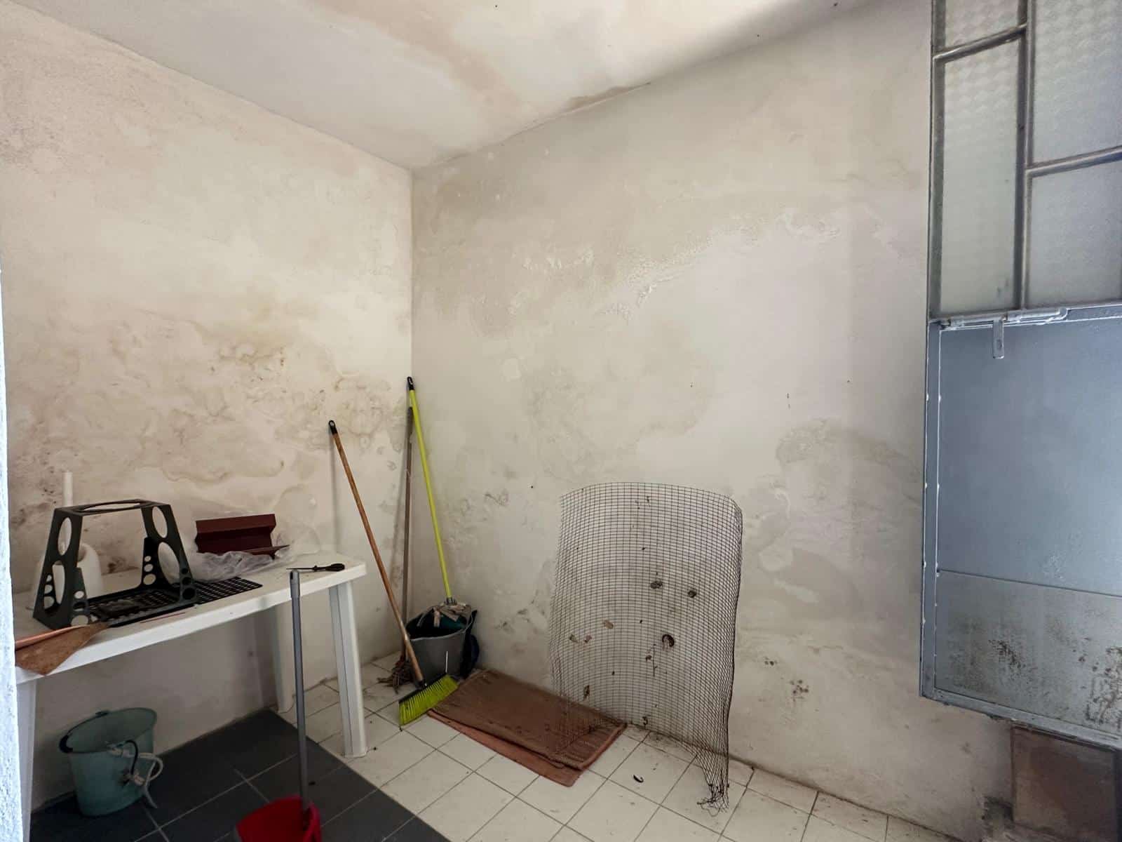 Sgombero ufficio o locale in ristrutturazione con pareti in stucco e zona calpestabile, attrezzature per pulizia e sgombro, ambiente luminoso e pratico, pronto a essere arredato o rinnovato.