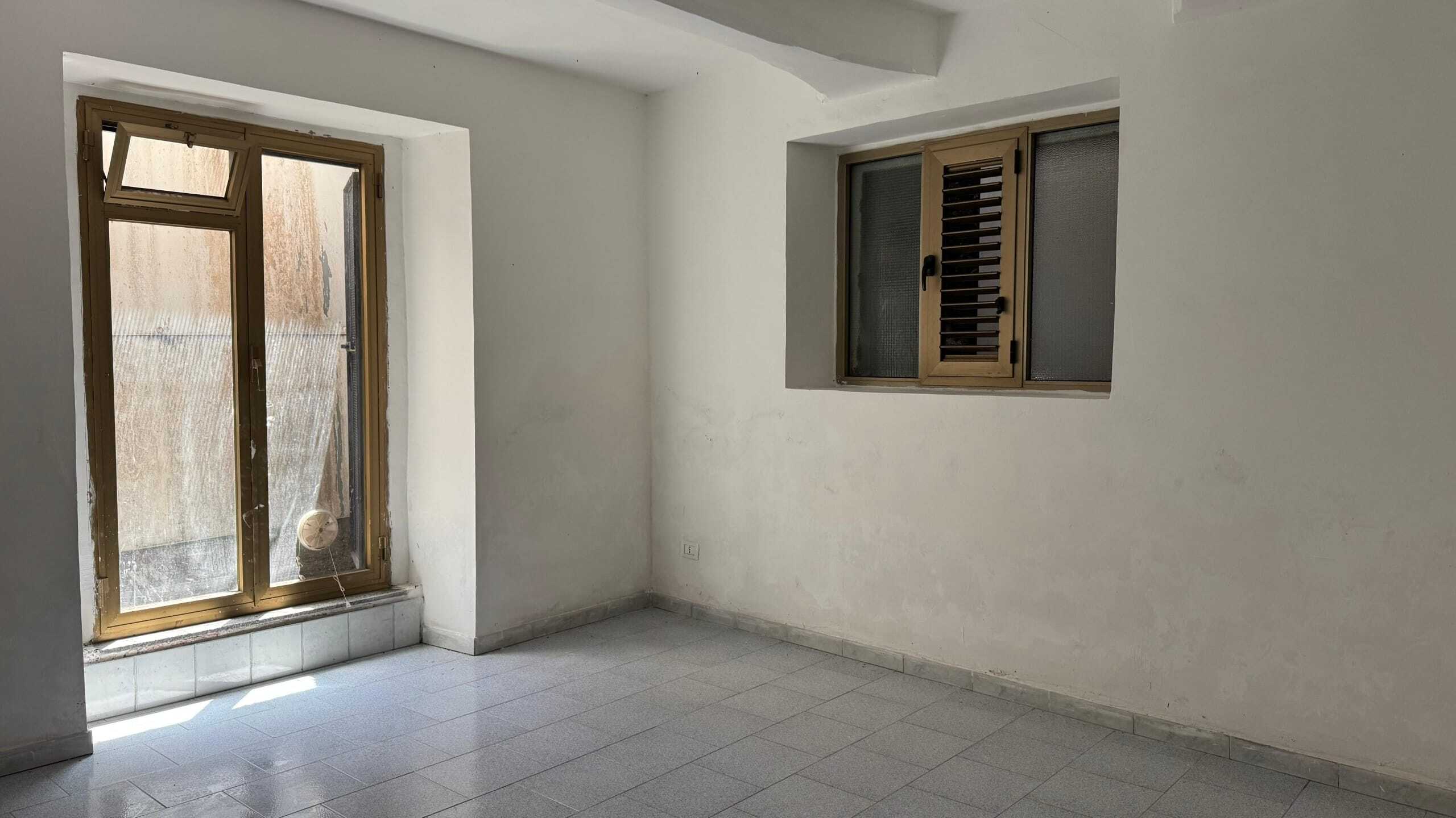 Vano vuoto con finestre a battente in alluminio e pareti bianche, pronto per essere arredato, ideale per chi cerca soluzioni immobiliari a NextCasa.