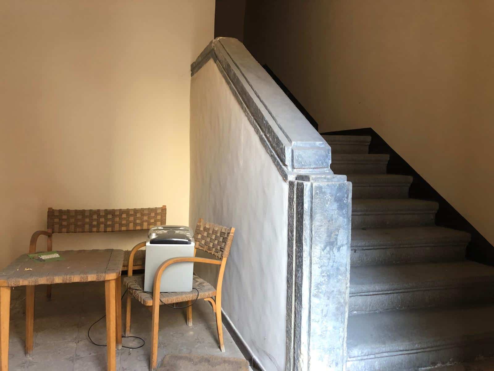 Risorsa abitativa con scala in pietra e area soggiorno con tavolo in legno e sedie in vimini, situata in un contesto residenziale di alta qualità.