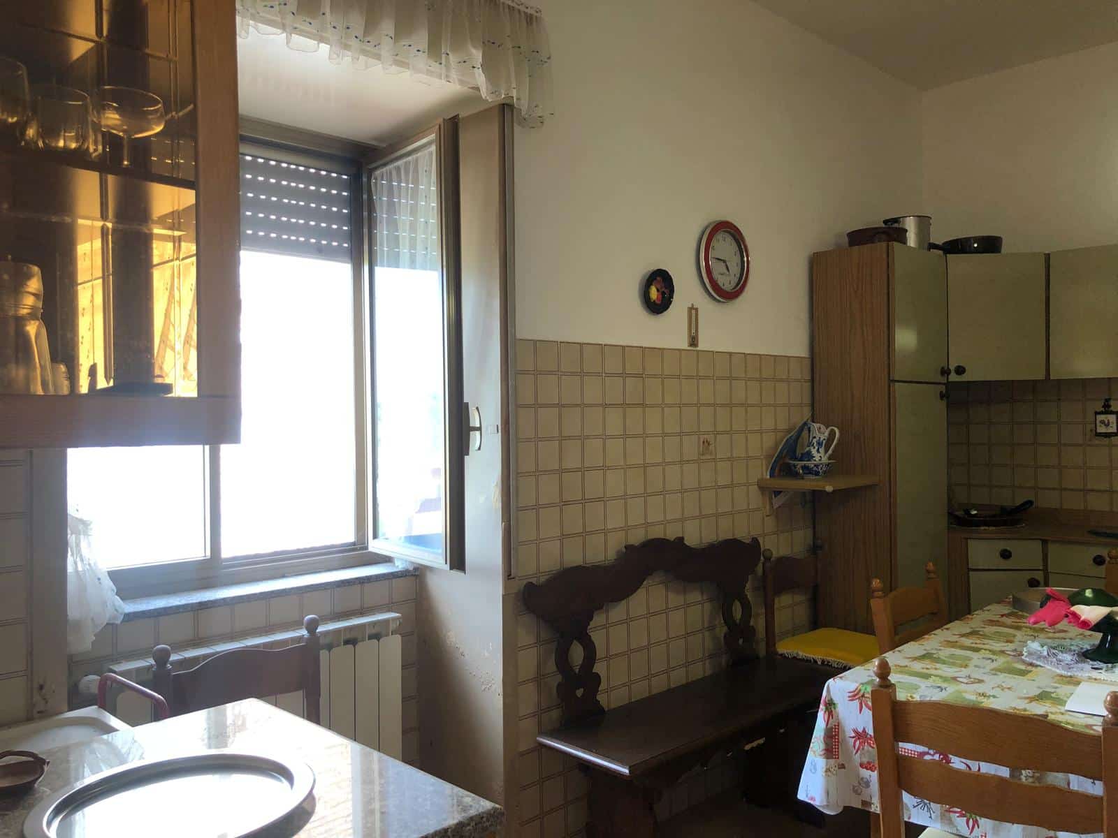 Vecchia cucina abitabile con finestra e mobili dal gusto vintage, ideale per case di montagna o appartamenti preservati nel tempo, perfetta per chi cerca un ambiente accogliente e ricco di storia.