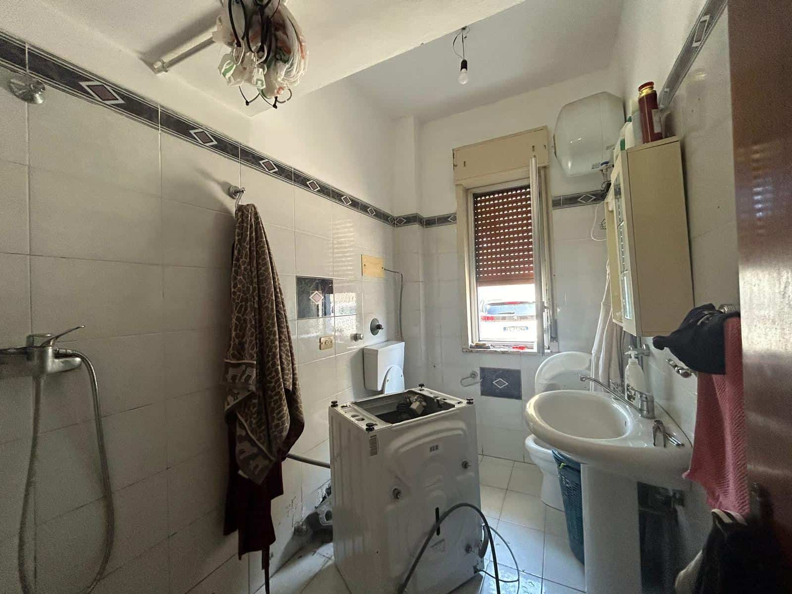 Lavanderia piccola con lavatrice, lavabo, asciugatrice, finestra, supplementi per la pulizia e arredo funzionale, in stile semplice e pratico, ideale per residenze.