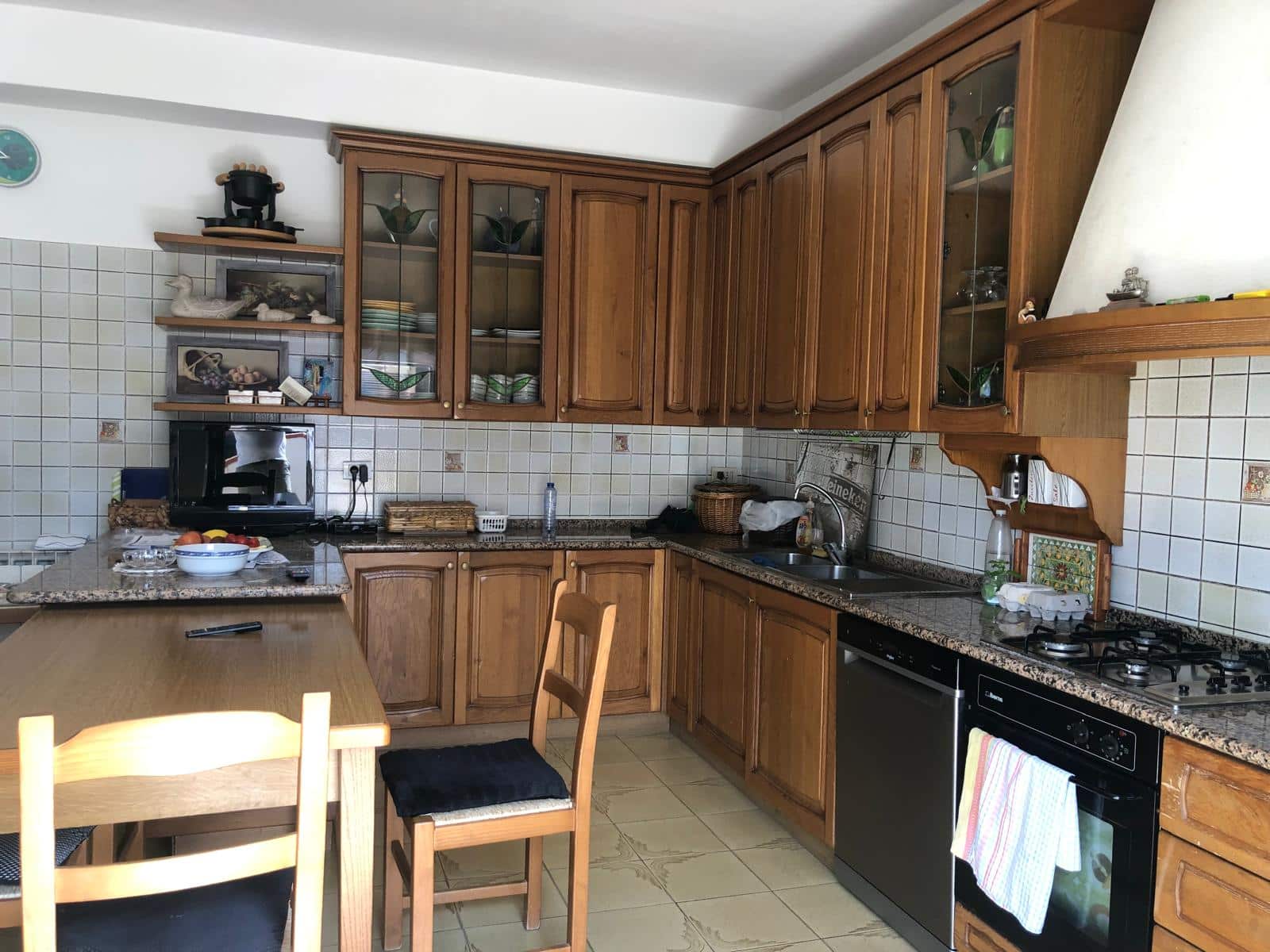 Cartongio in legno rustico, cucina abitabile con piani in granito, elettrodomestici moderni, stoviglie e decorazioni domestiche, ambiente accogliente e funzionale, ideale per la casa di famiglia.