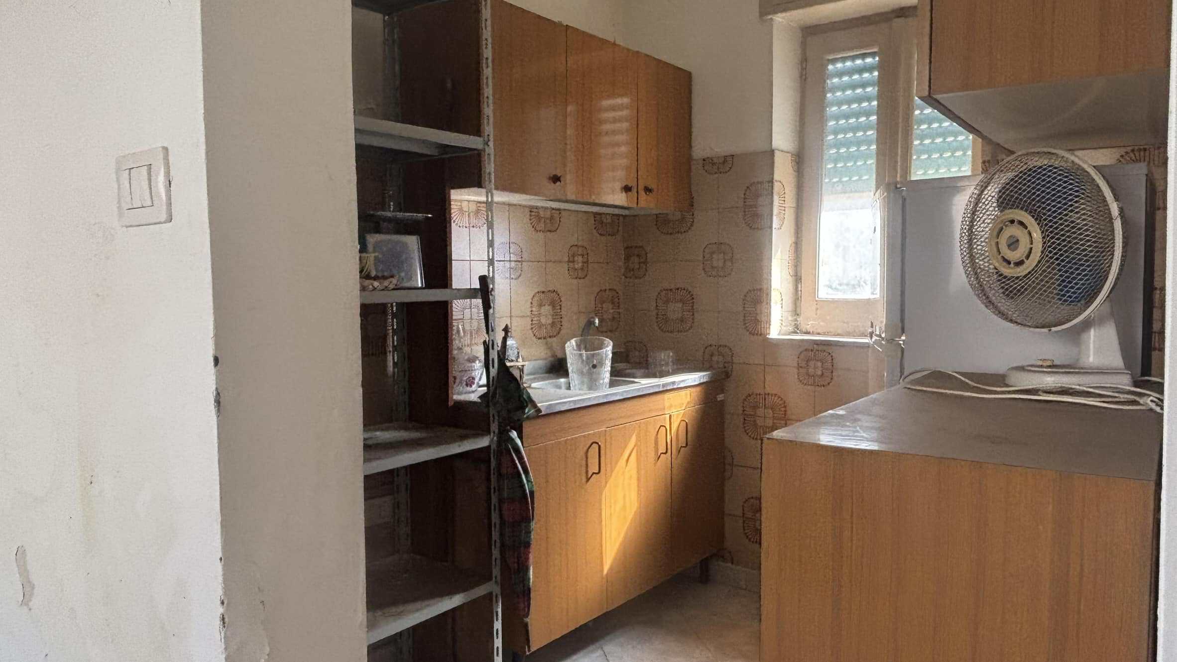 Lavanderia piccola con cucina in stile vintage, finestra che lascia entrare luce naturale, mobili in legno e dettagli anni 70, ideale per un appartamento in città.