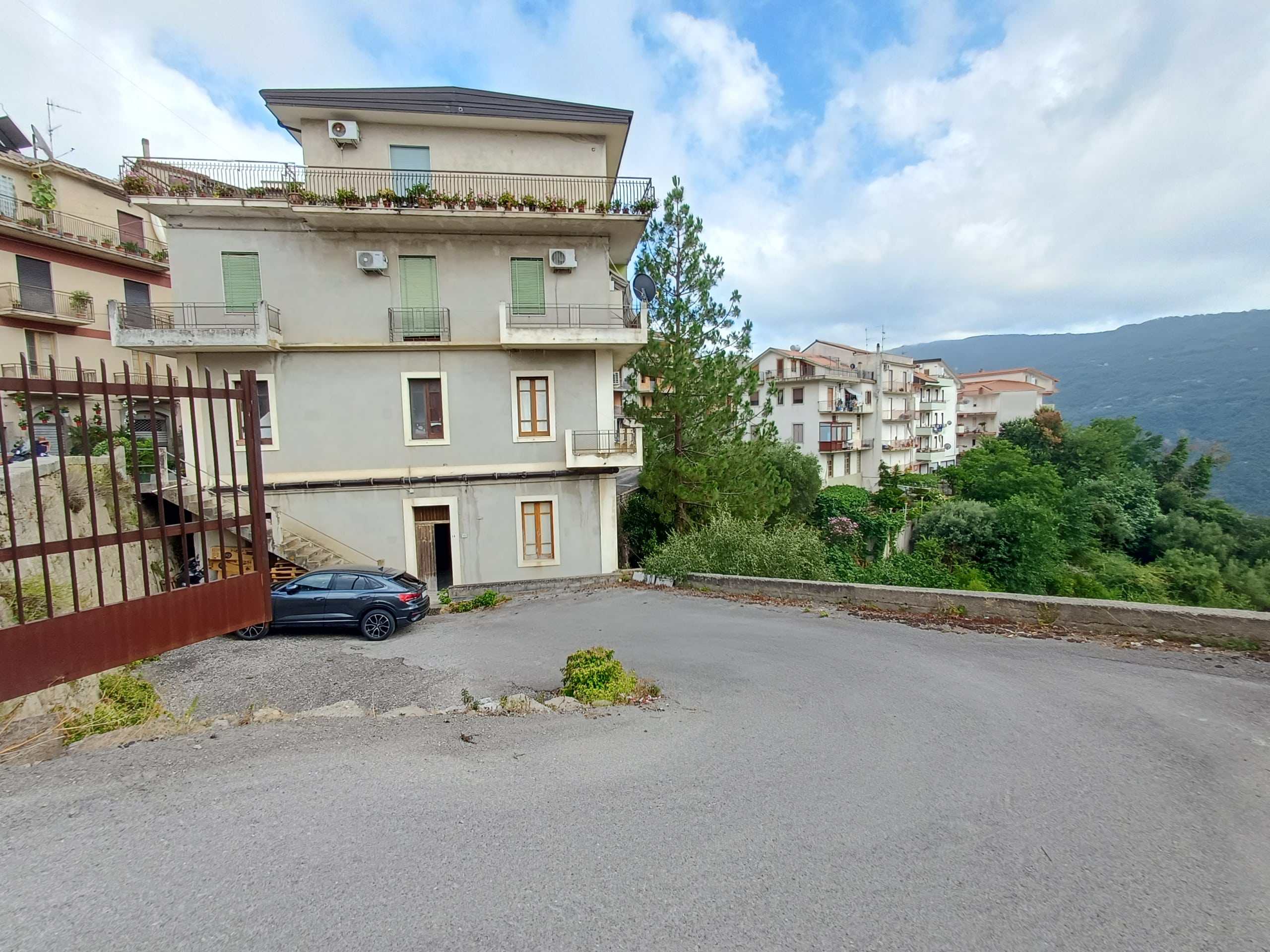 Ampio parcheggio esterno di fronte a edificio residenziale con vista sulle montagne, ideale per clienti NextCasa alla ricerca di soluzioni immobiliari in zona panoramica.