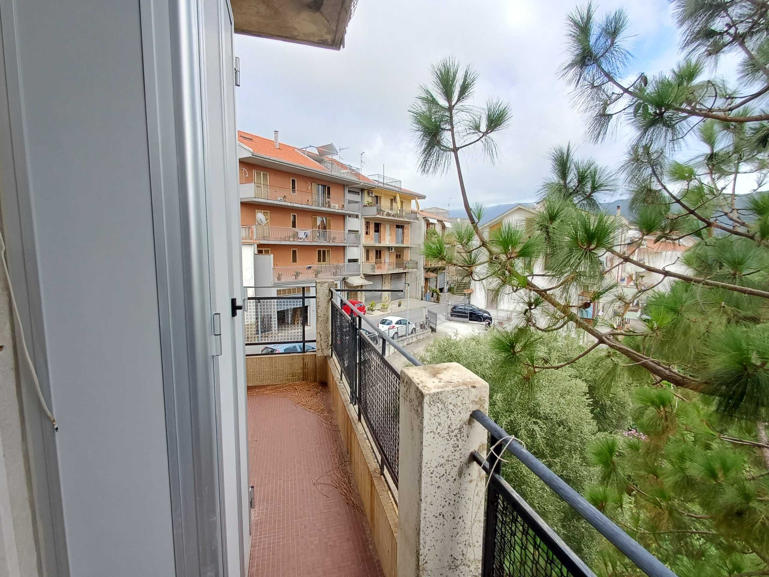 Splendida vista dal balcone di un appartamento vicino alle montagne, con alberi verdi e edifici residenziali in background, ideale per vivere in un quartiere tranquillo e immerso nella natura.