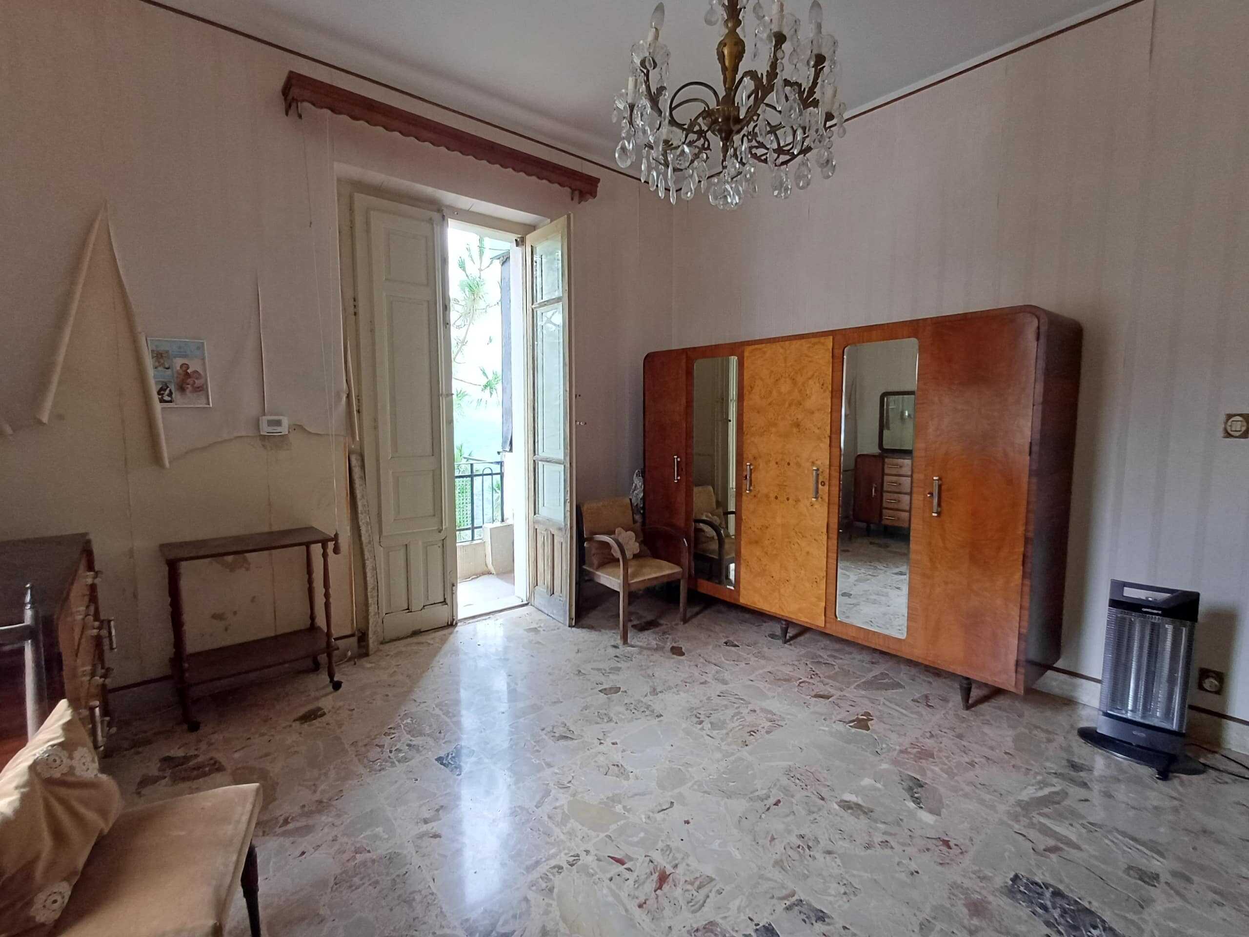 Armadio d'epoca in legno con specchi, mobili vintage in stile classico, arredamento soggiorno storico, paesaggio interno con lampadario a cristalli e porta balcone, atmosfera antica ed elegante.
